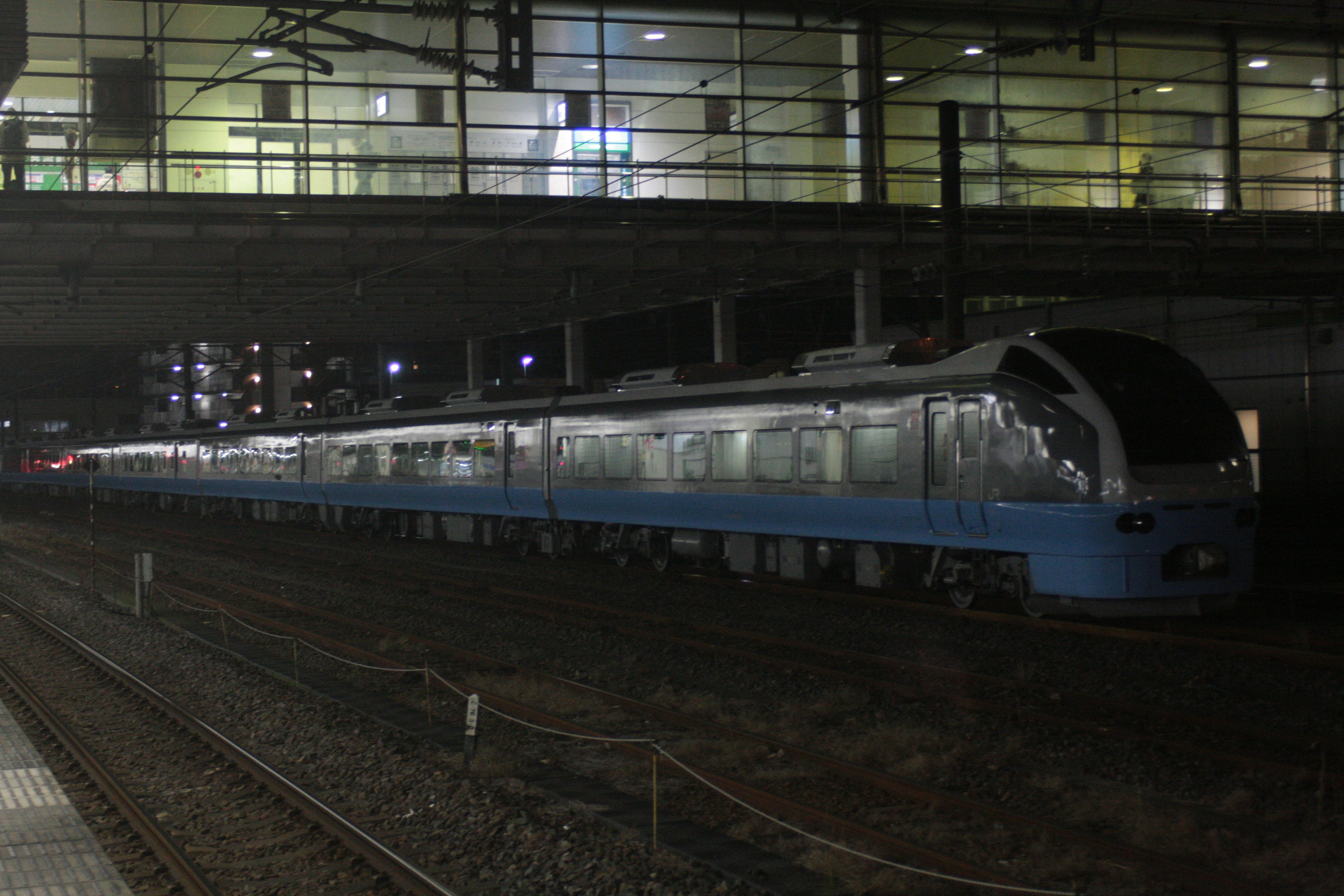 A blue train stopped at a station during nighttime