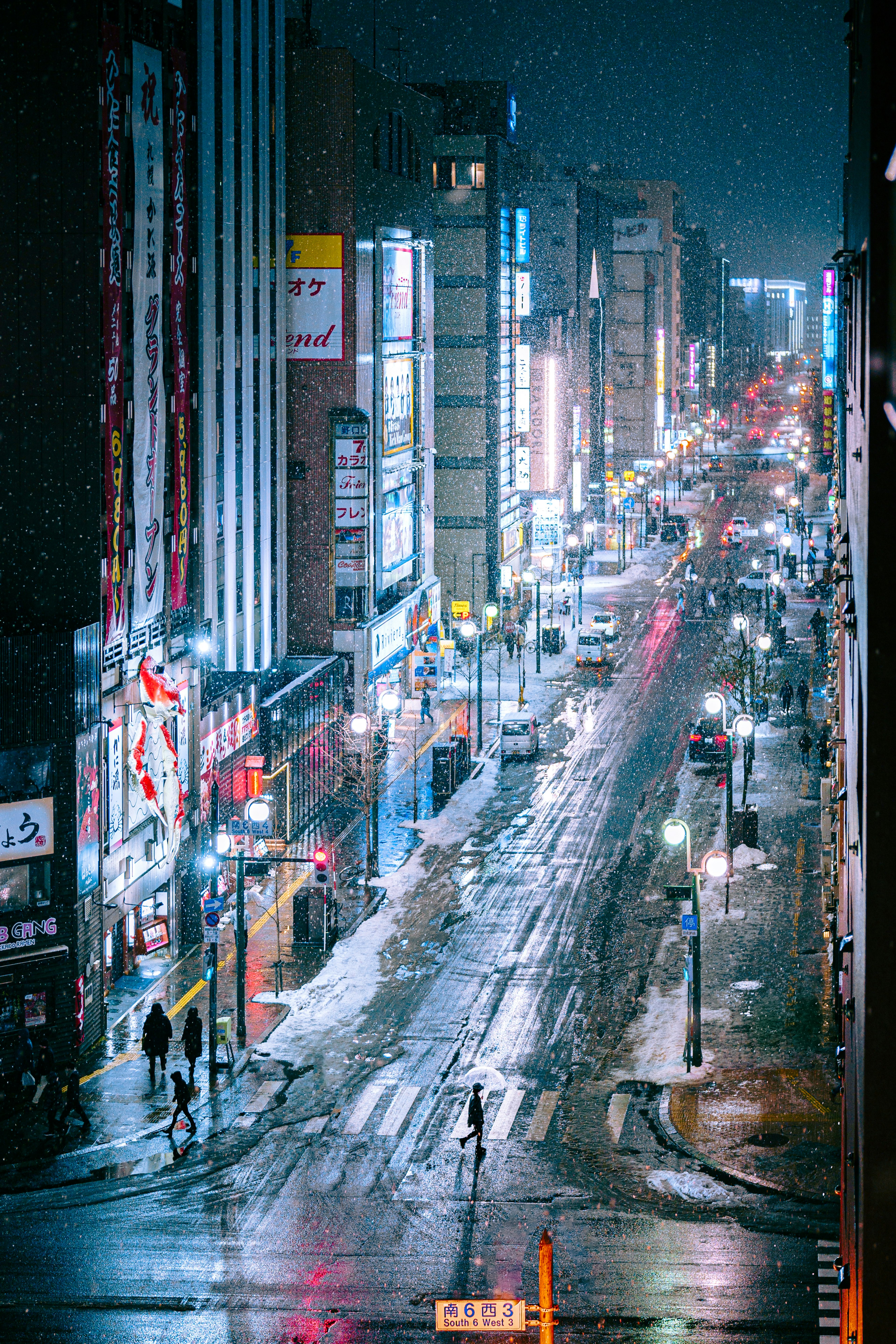 City street in snow with bright neon signs and wet pavement