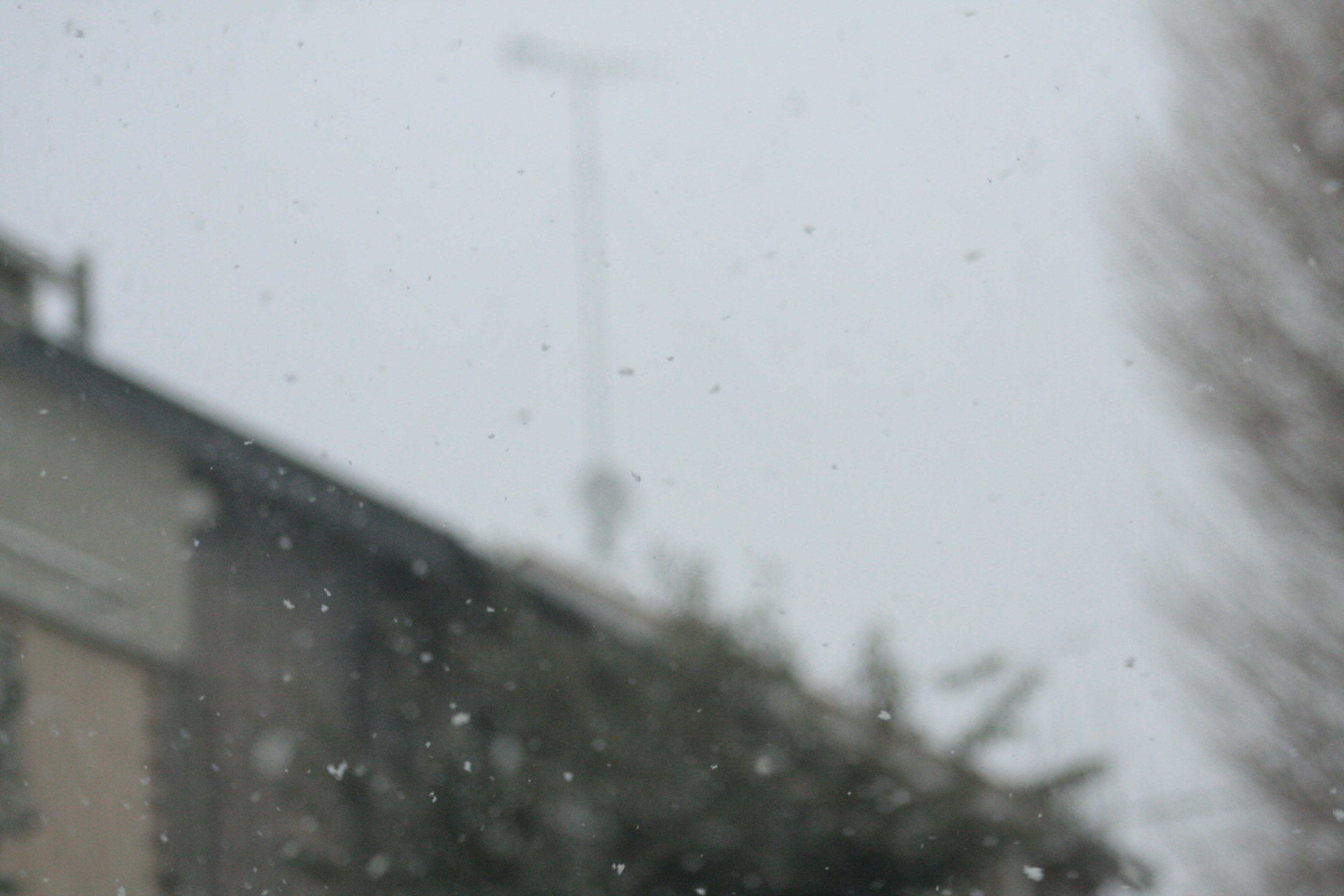 A house roof with an antenna in falling snow