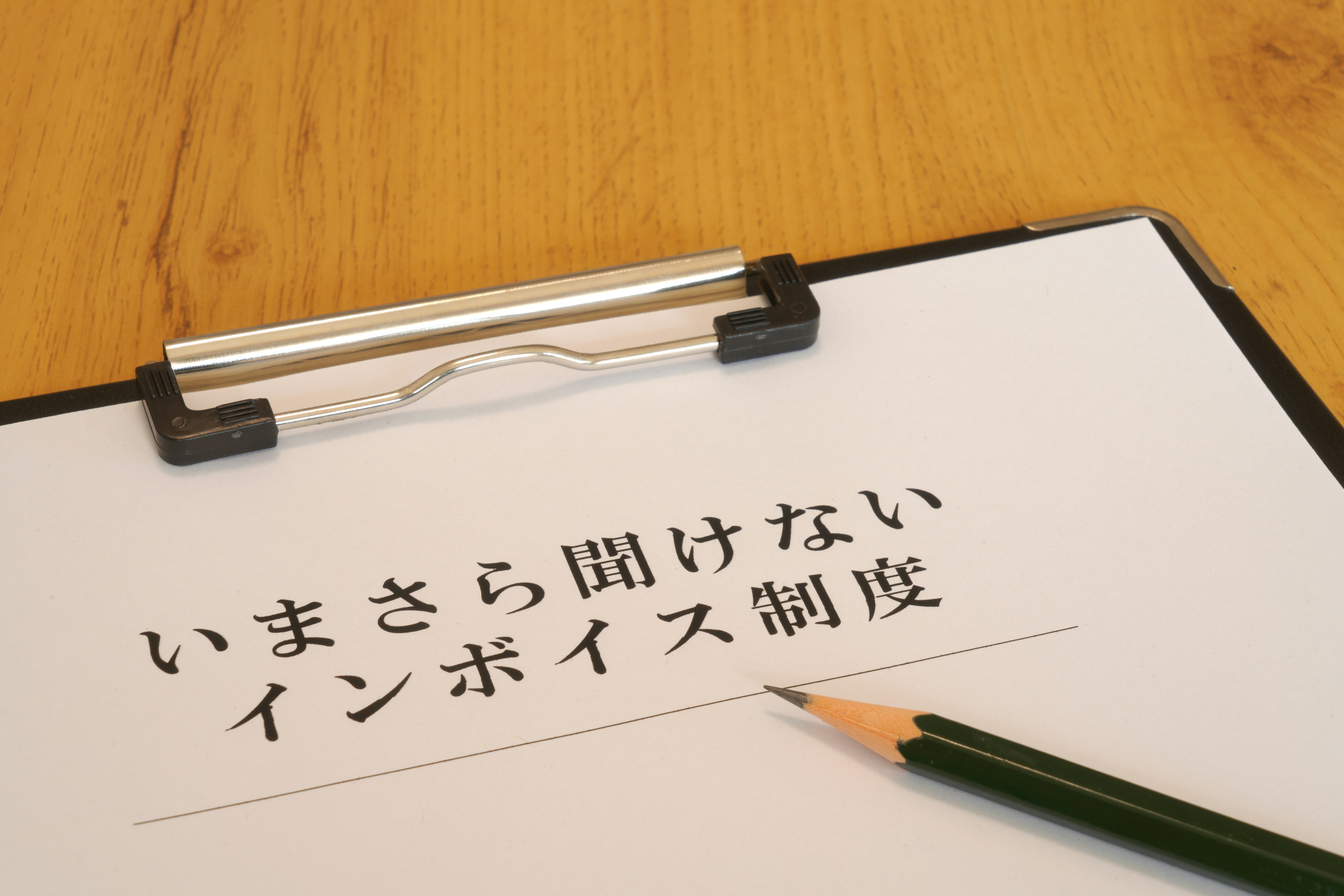 A white sheet of paper with Japanese text on a clipboard and a green pencil