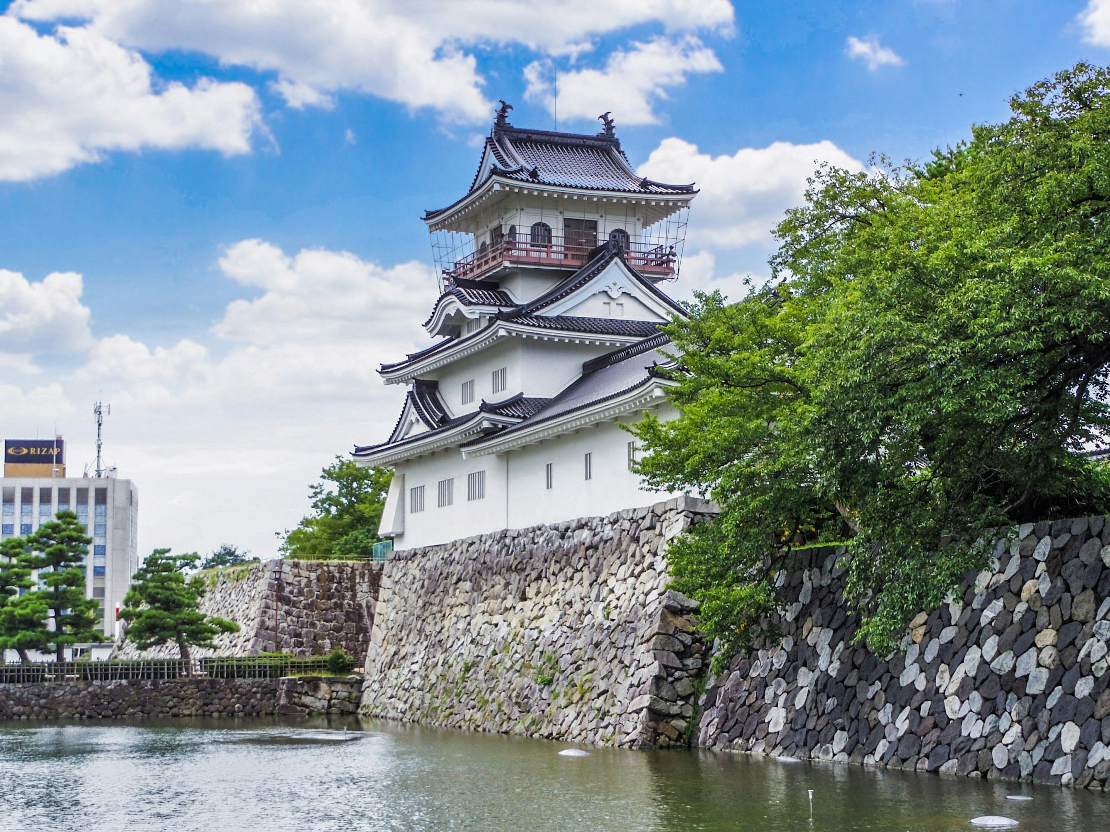 A castle exterior beside a serene body of water and blue sky