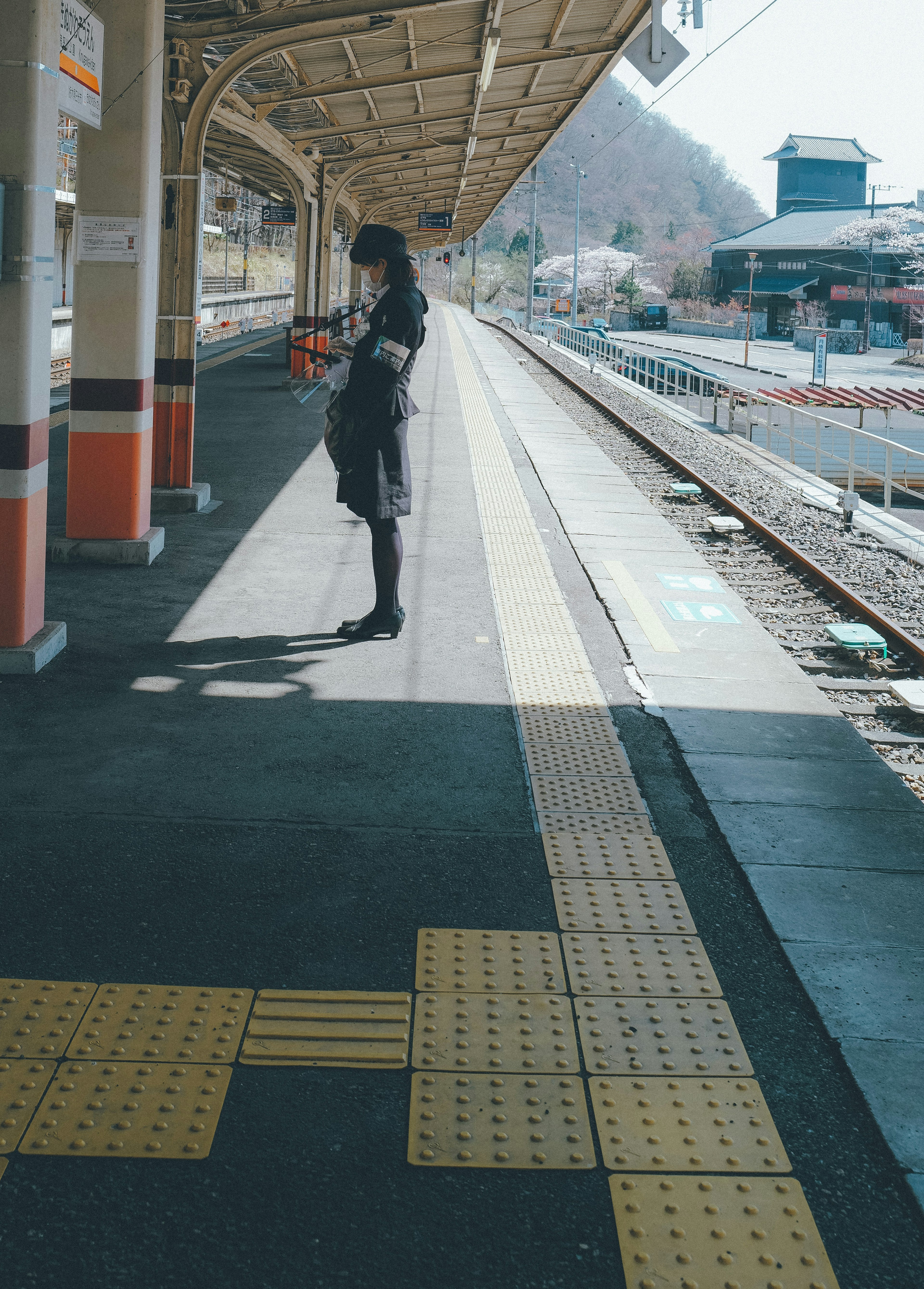 Siluet seorang wanita berdiri di platform stasiun kereta yang tenang