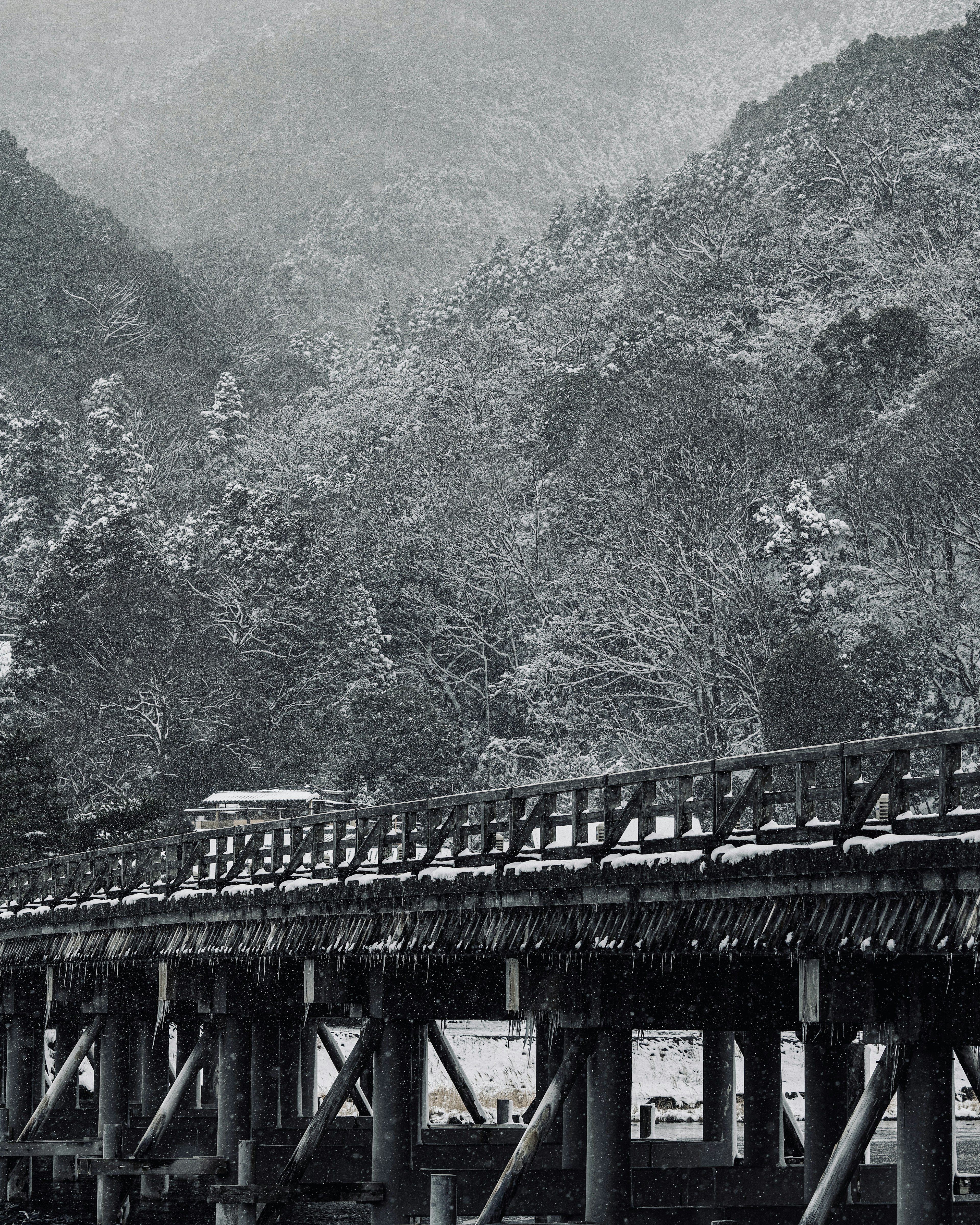 Monochrome landscape of snow-covered mountains and a wooden bridge