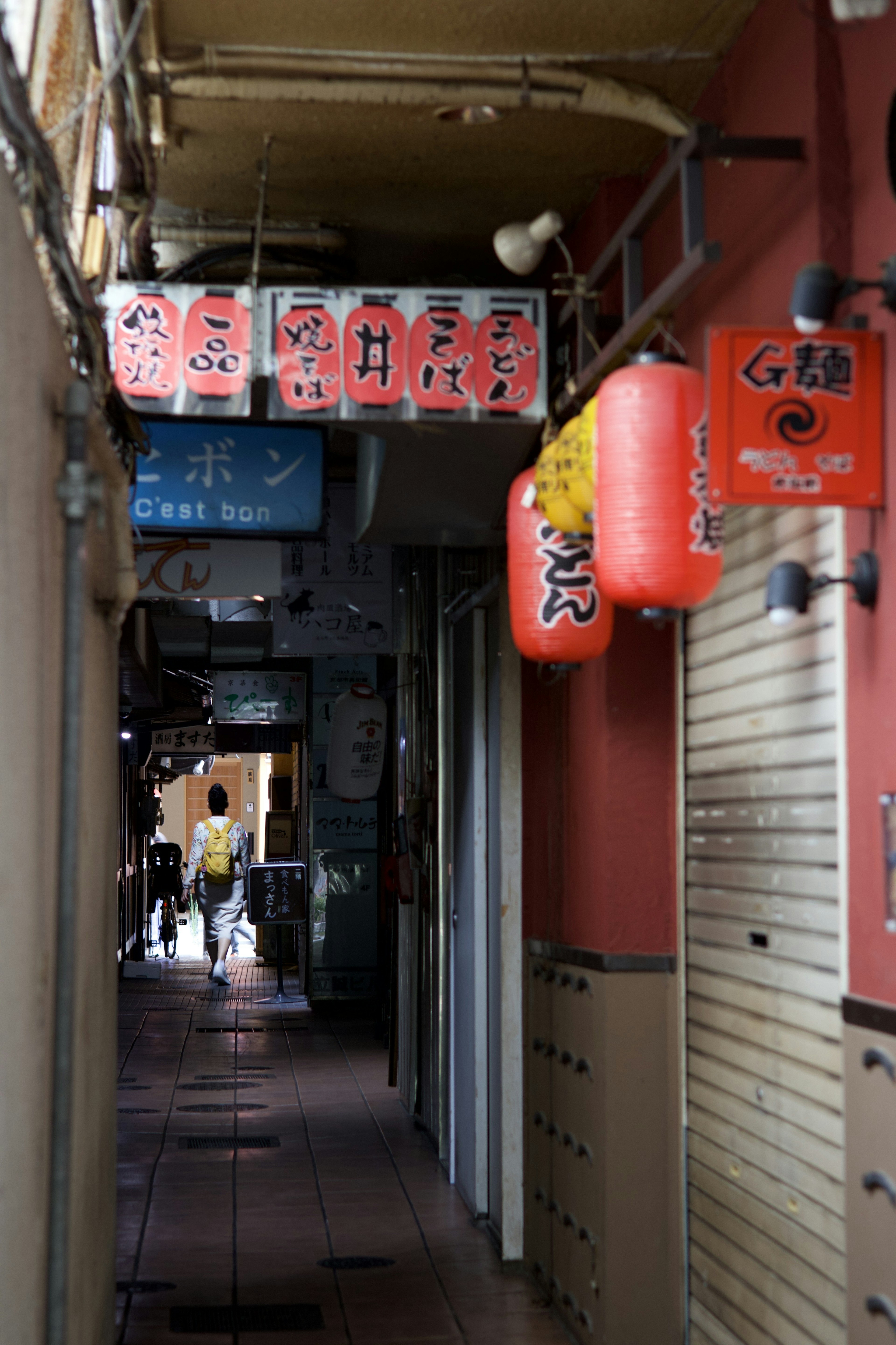 Ruelle étroite bordée de panneaux de restaurants et de lanternes rouges