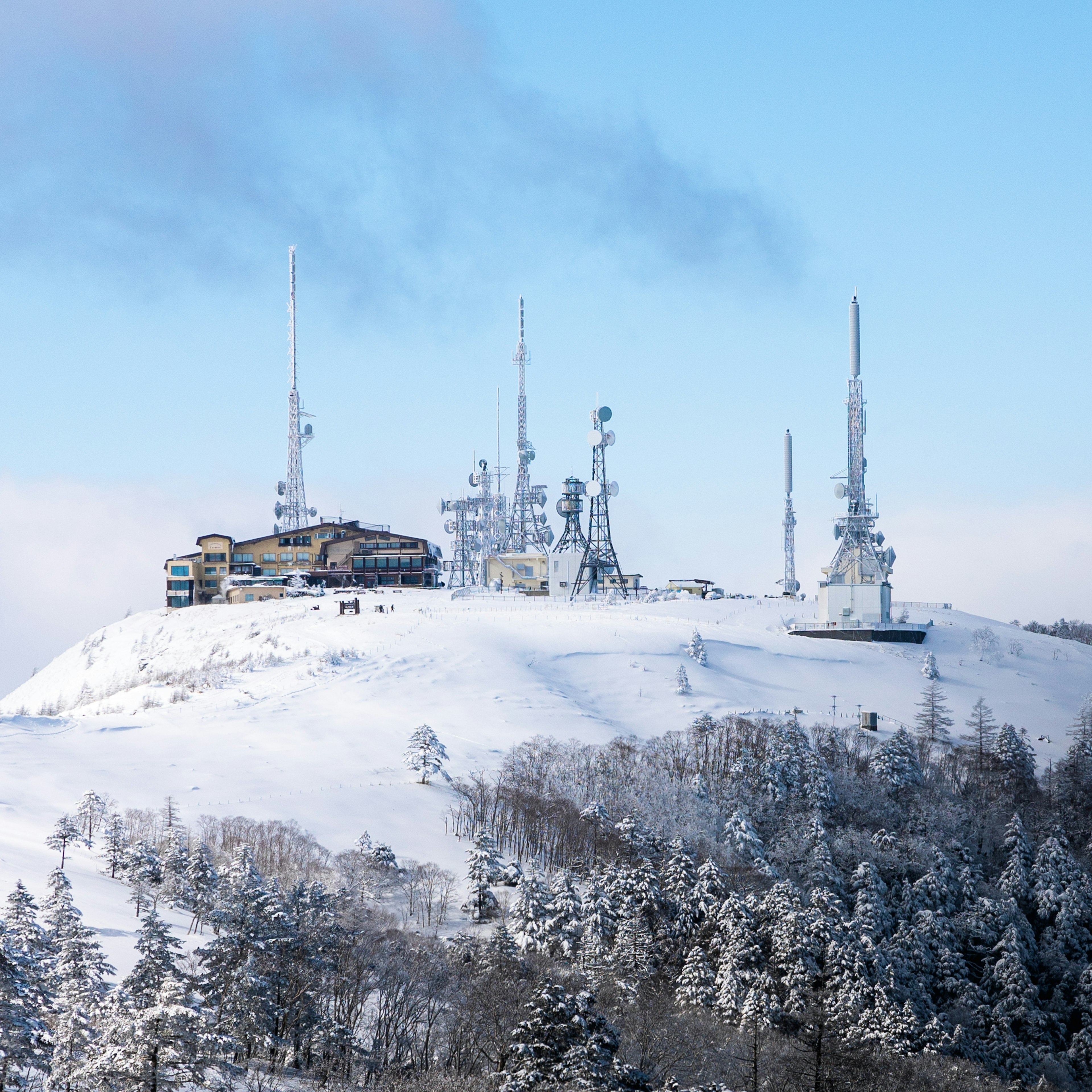 雪に覆われた山の頂上にある通信塔と建物