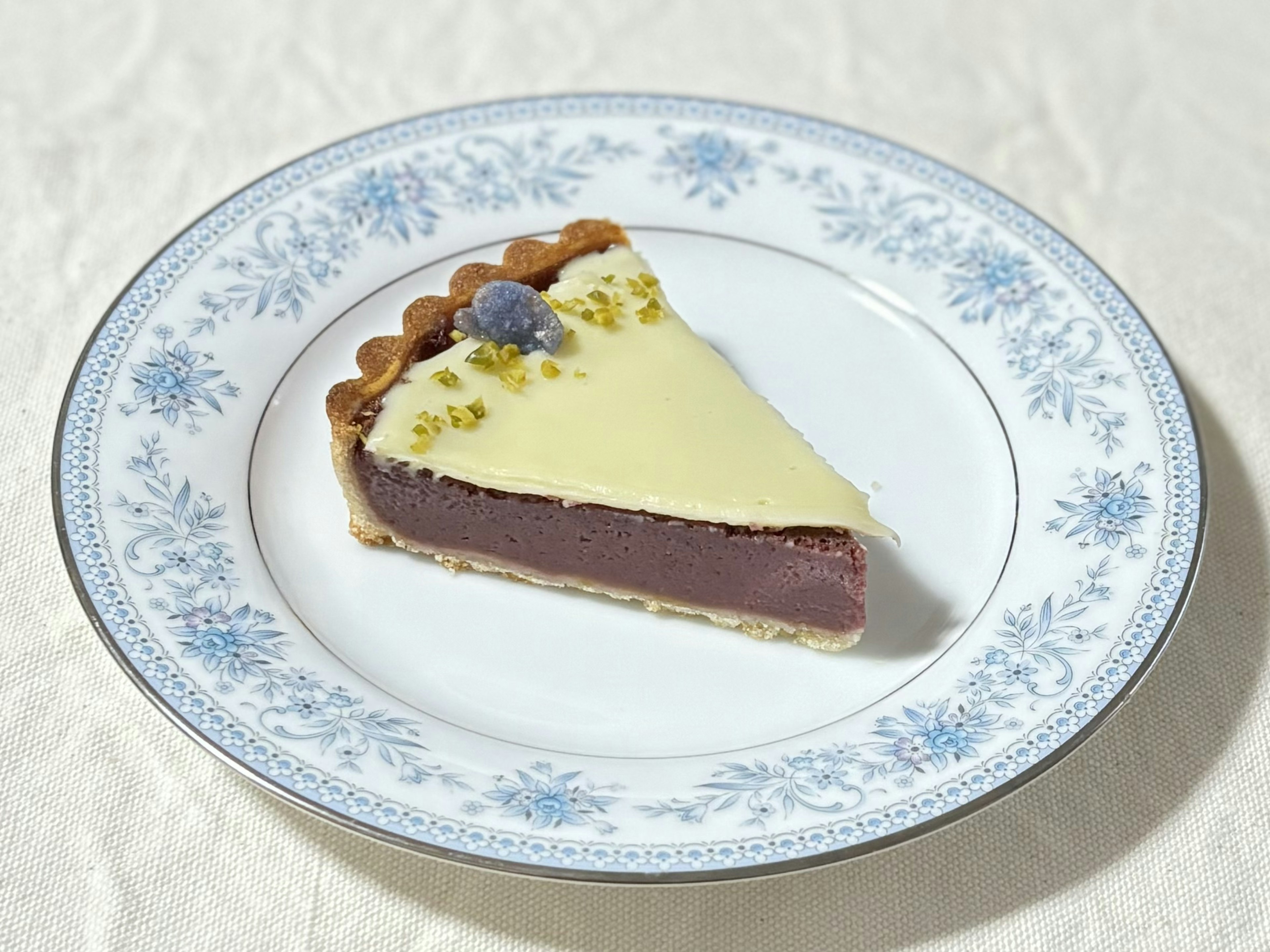 Une tranche de tarte au chocolat sur une assiette décorative avec un glaçage blanc