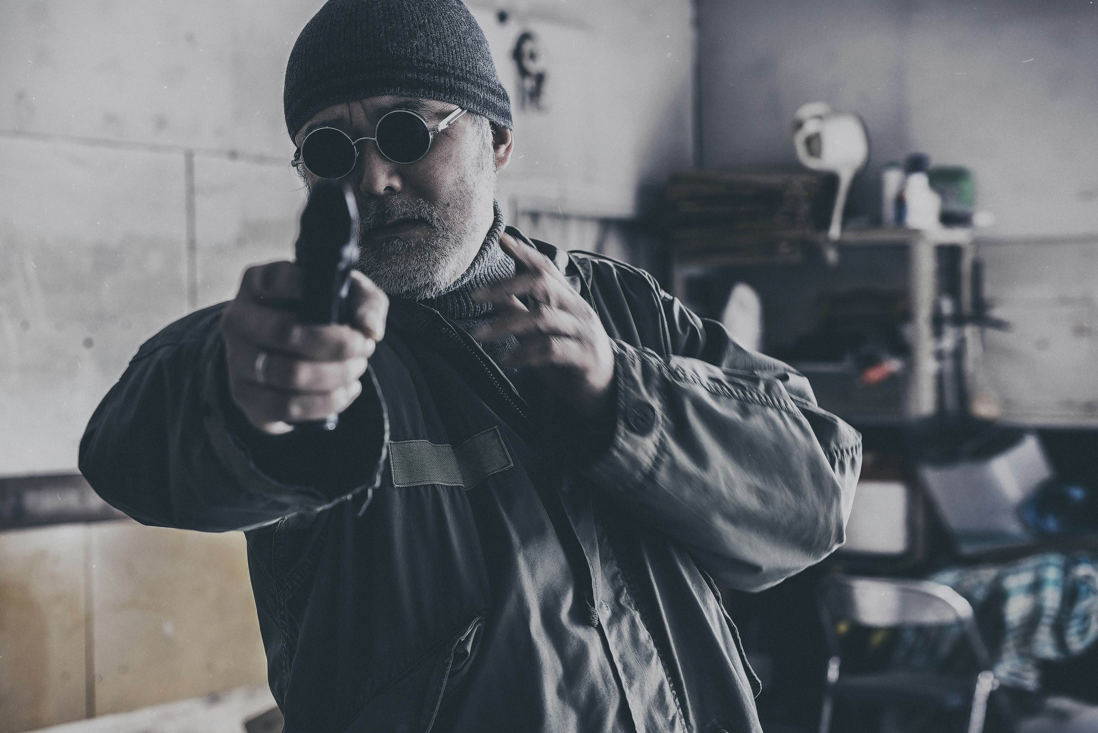 Man aiming a gun in a dimly lit room with a gritty background