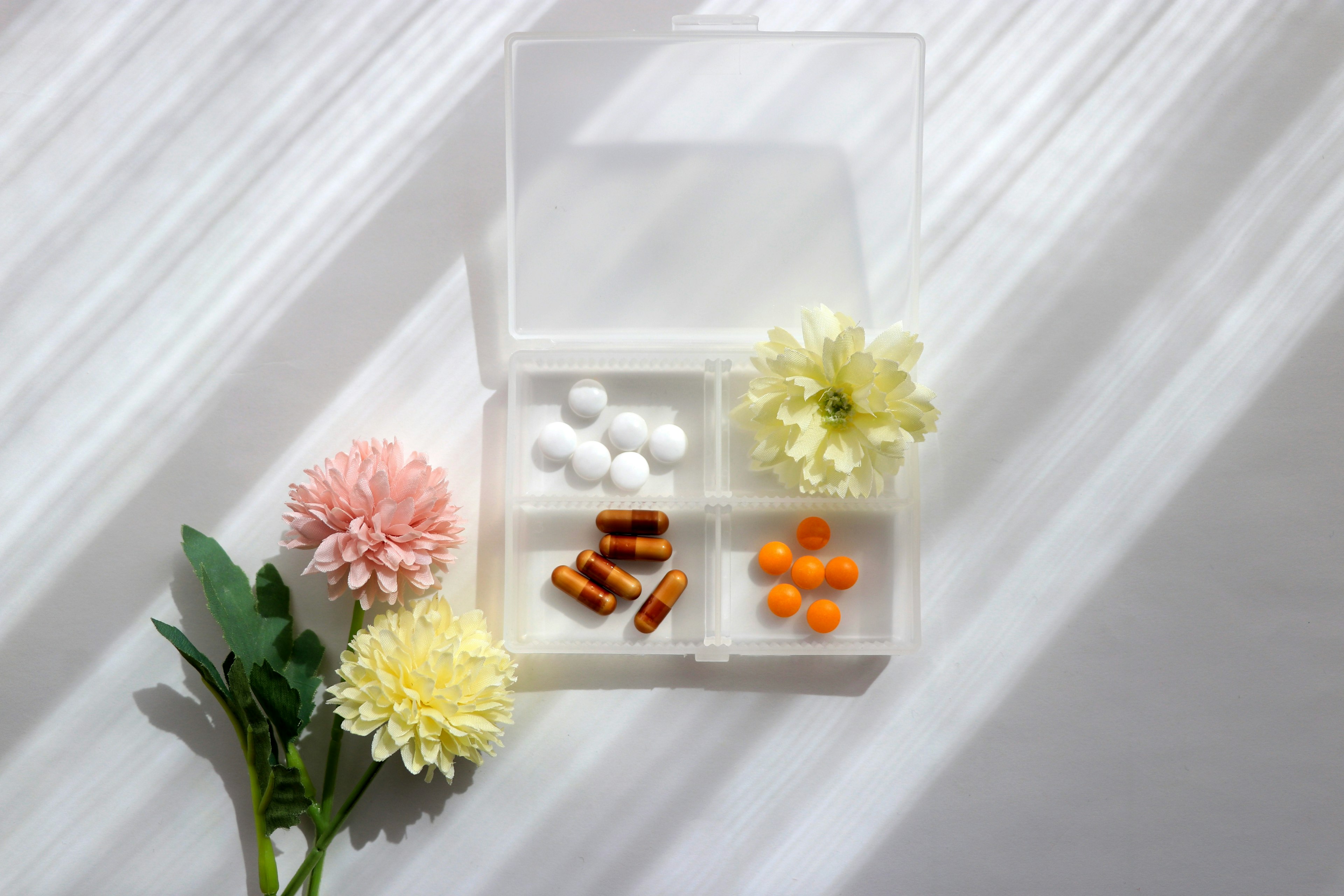 Una imagen simple con pastillas coloridas y flores sobre un fondo blanco