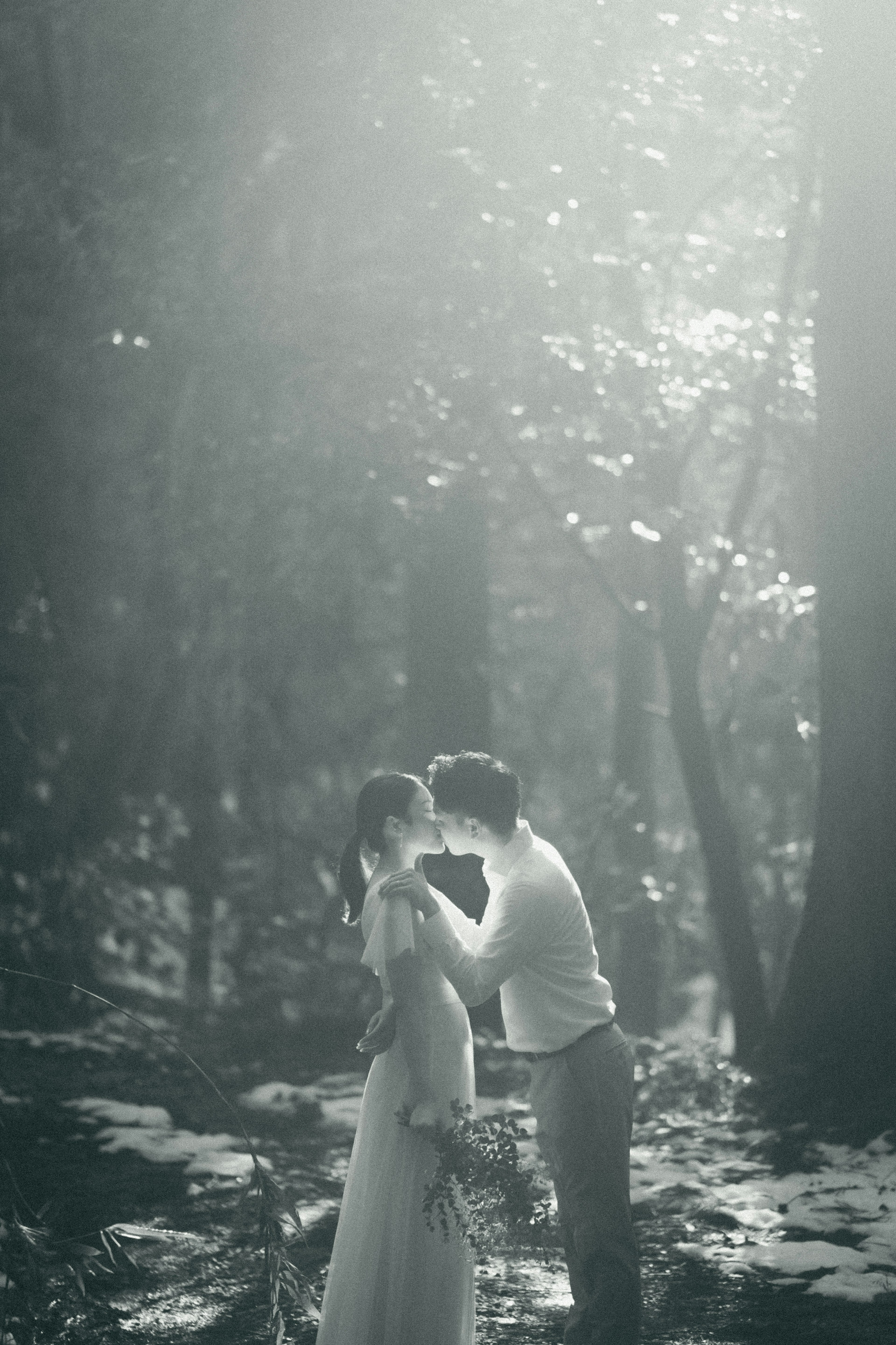 Silhouette of a bride and groom kissing in a dim forest