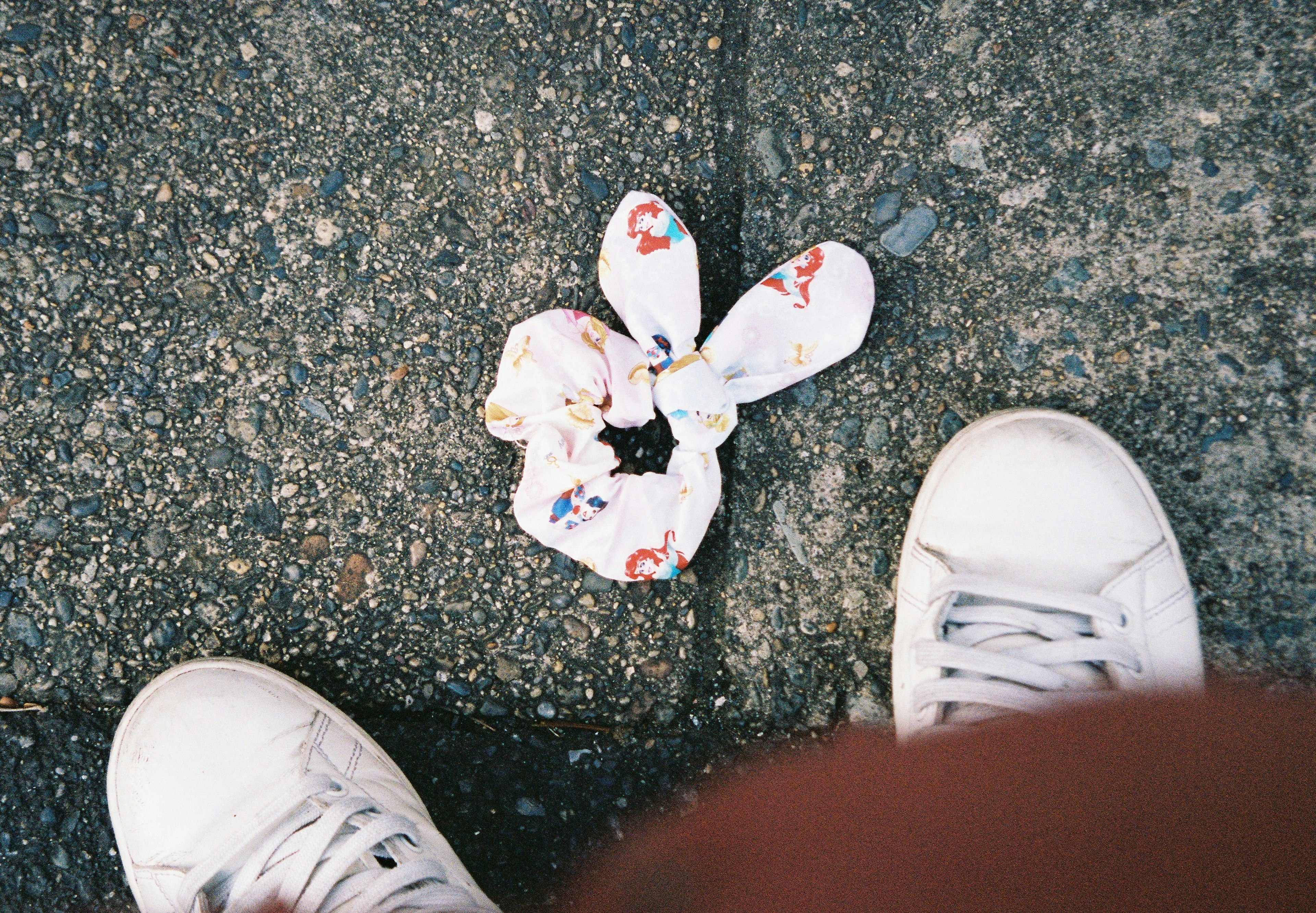 Scrunchie a fantasia floreale posato a terra vicino a scarpe bianche