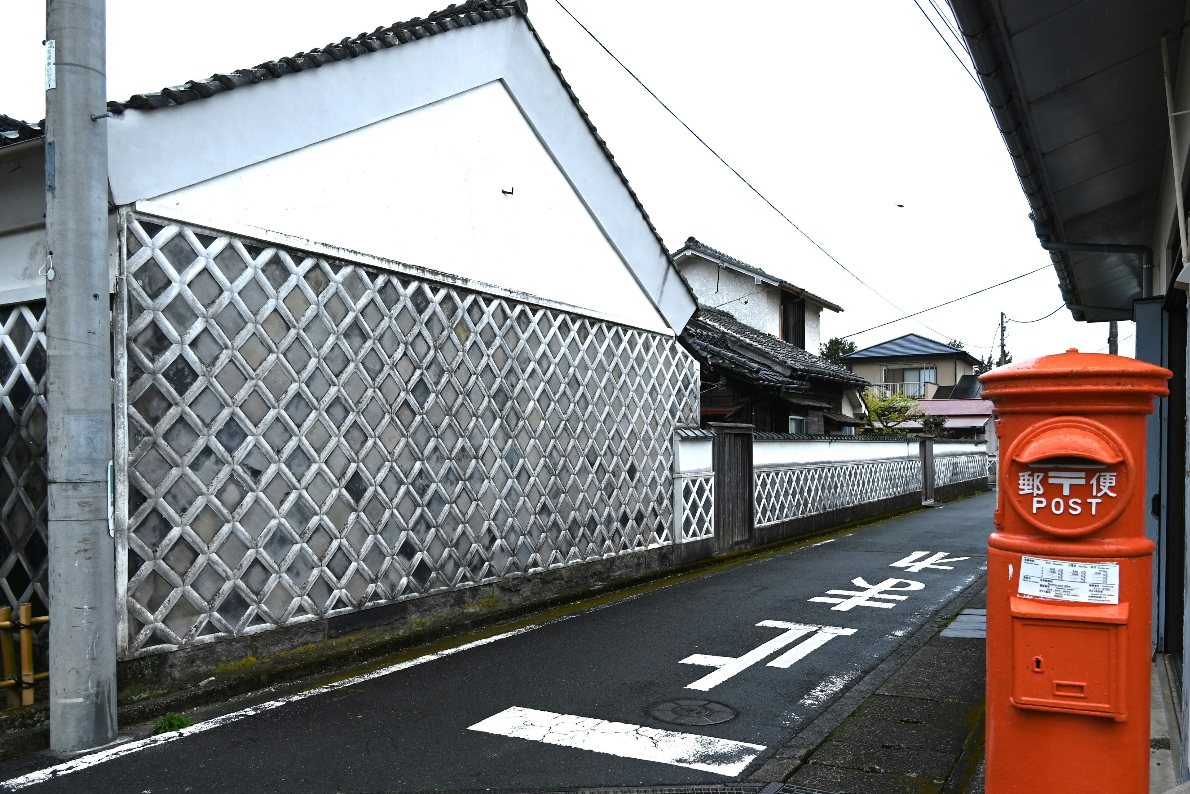 A quiet street scene featuring a red post box and traditional Japanese architecture