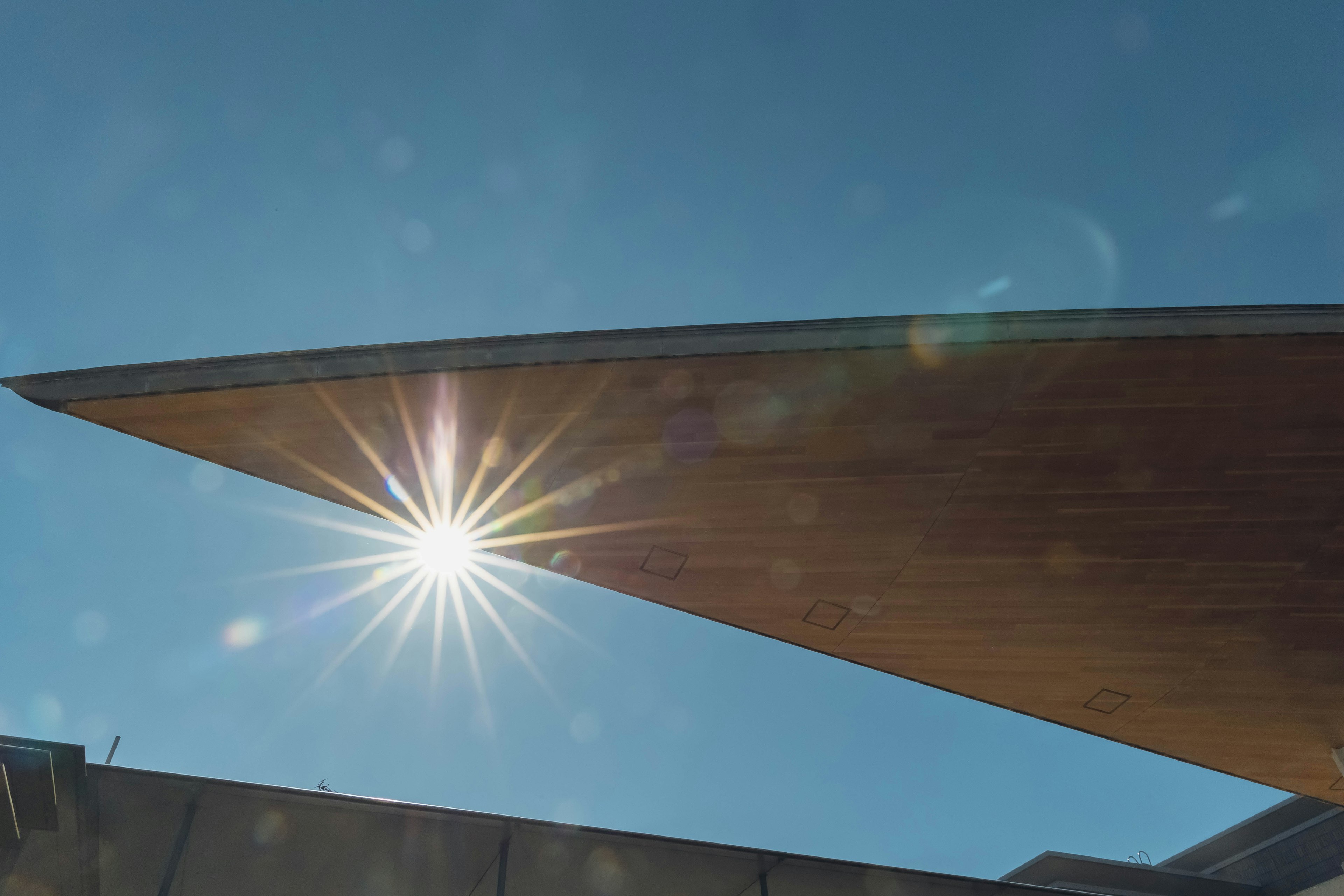 Architectural detail featuring a sharp roof edge with sunlight shining through