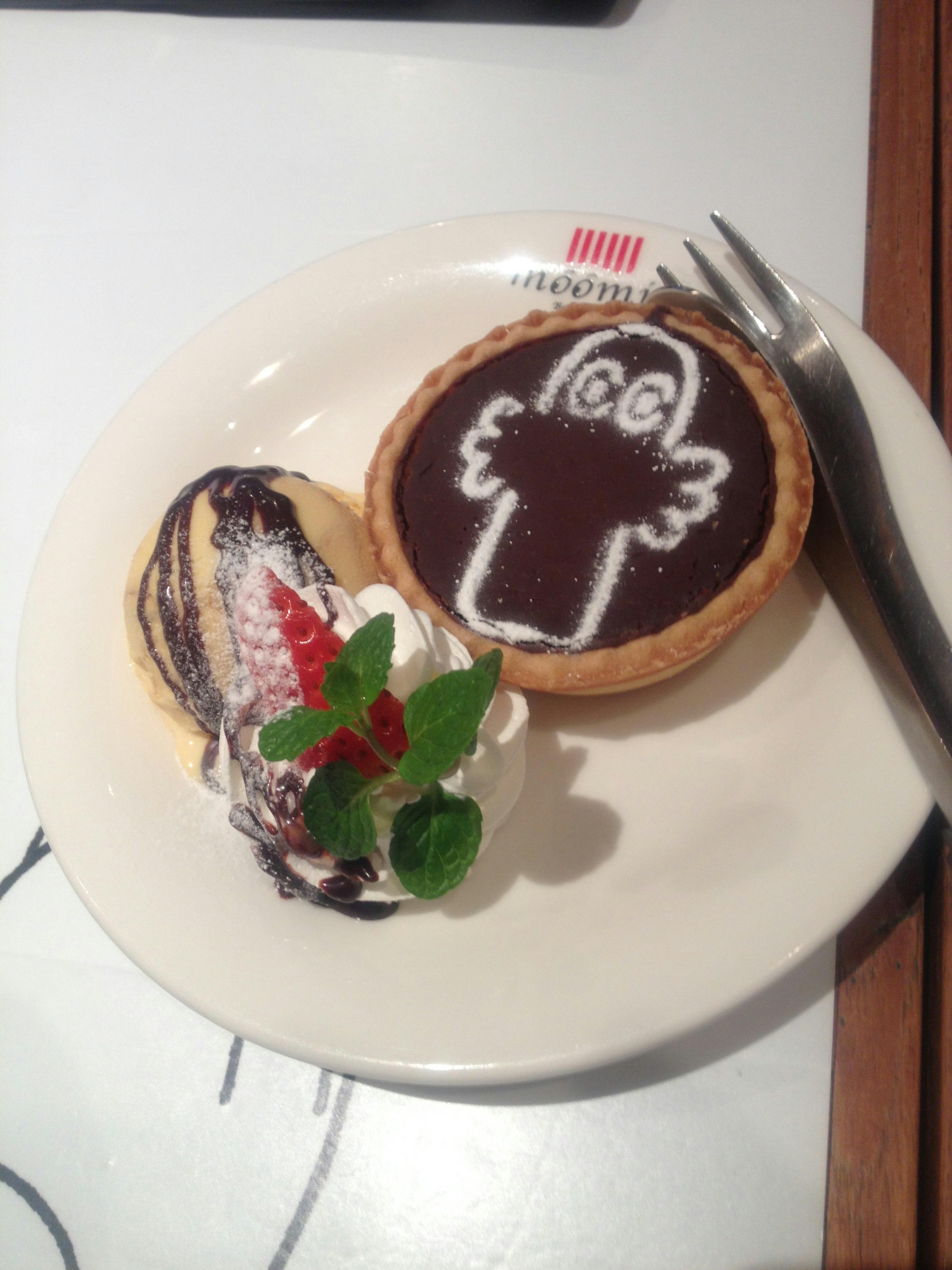 Chocolate tart with a cute character design and whipped cream dessert on a plate