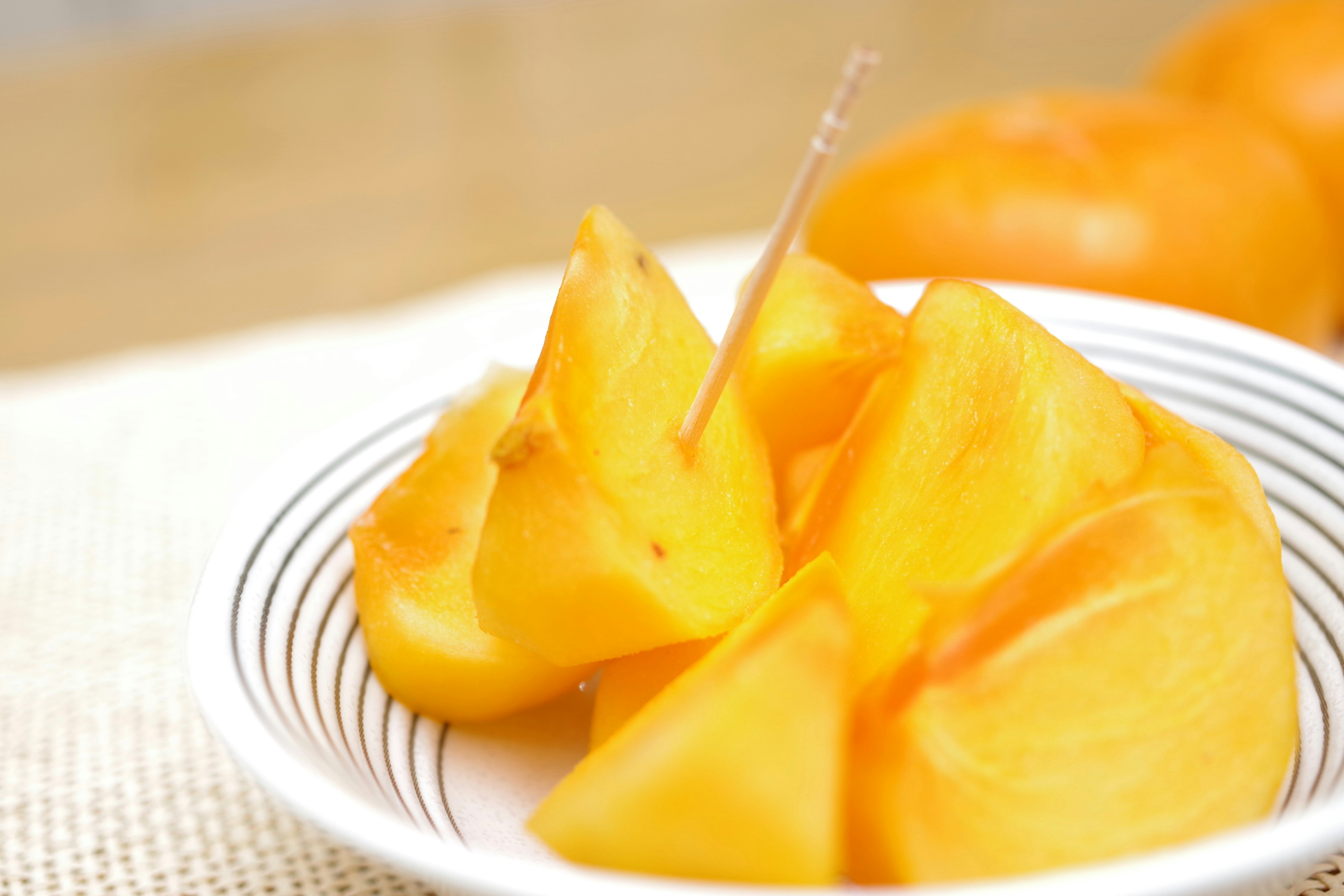 Rebanadas de fruta naranja dispuestas en un tazón blanco