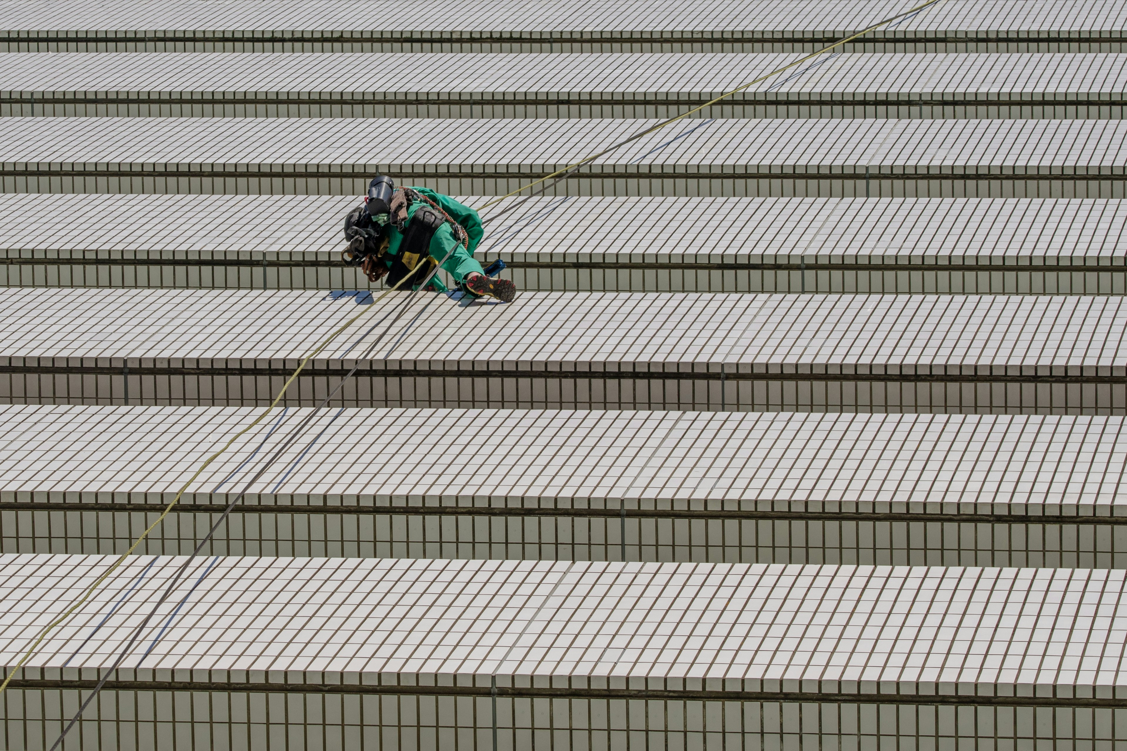 Trabajador en un techo con ropa de trabajo verde tejas de techo rectas visibles