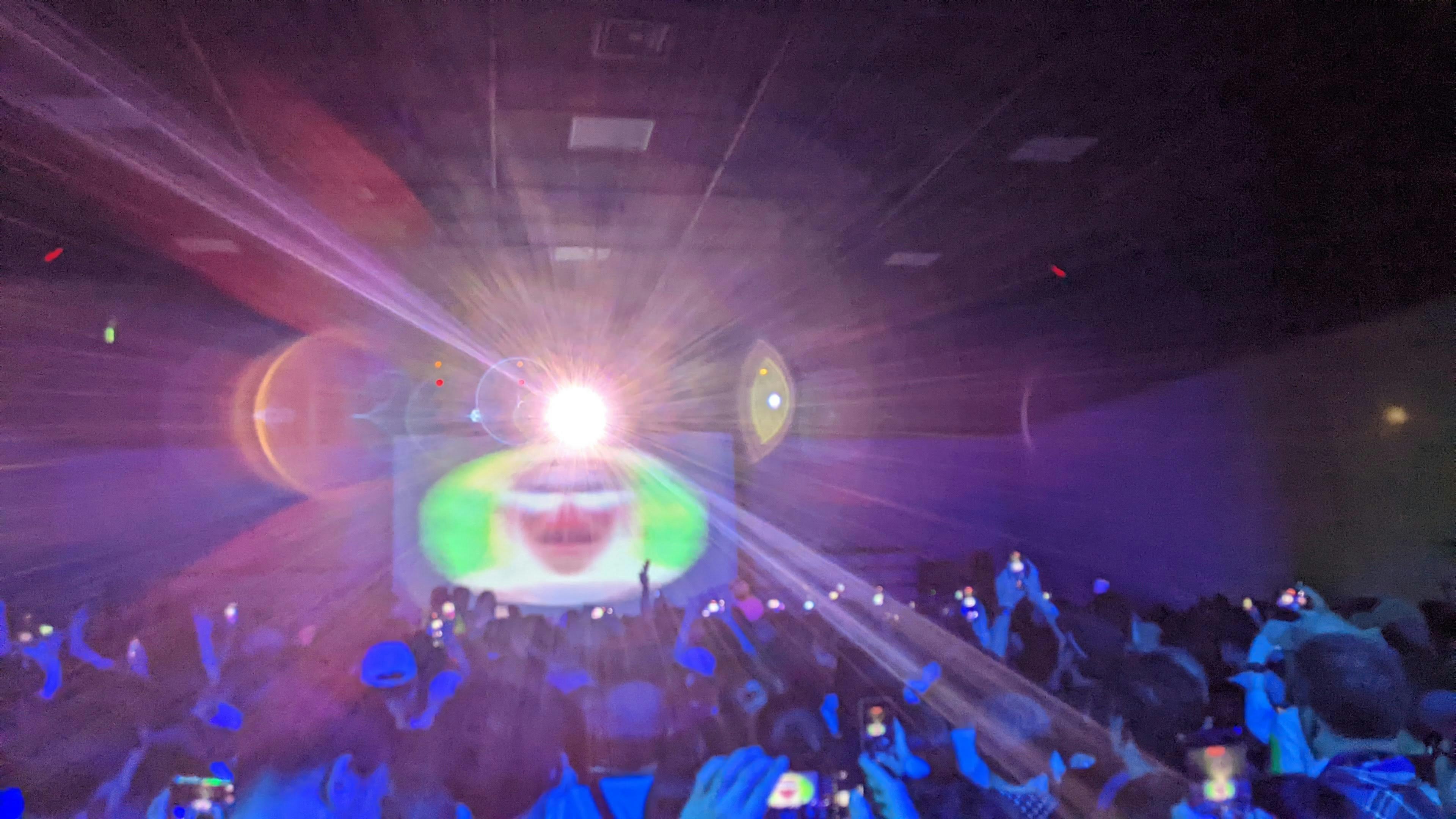 Pubblico che cattura un concerto con smartphone effetti di luce vivaci sul palco