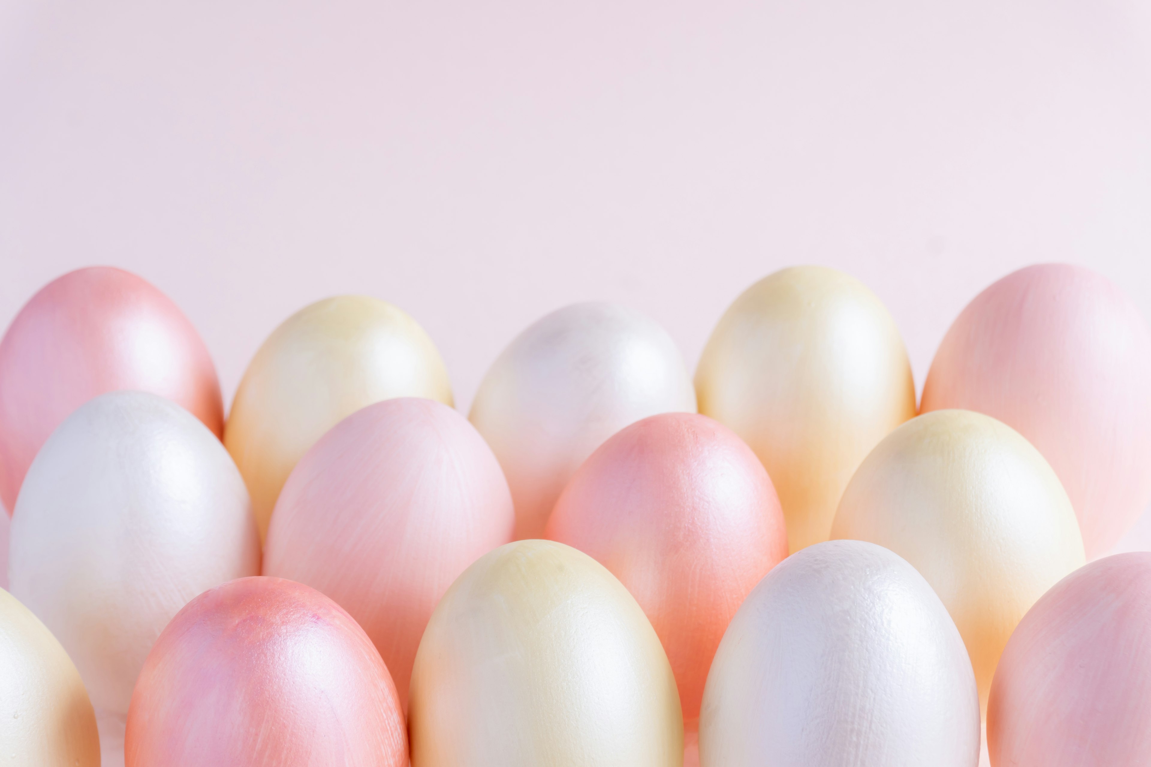 Colorful eggs arranged against a soft pink background