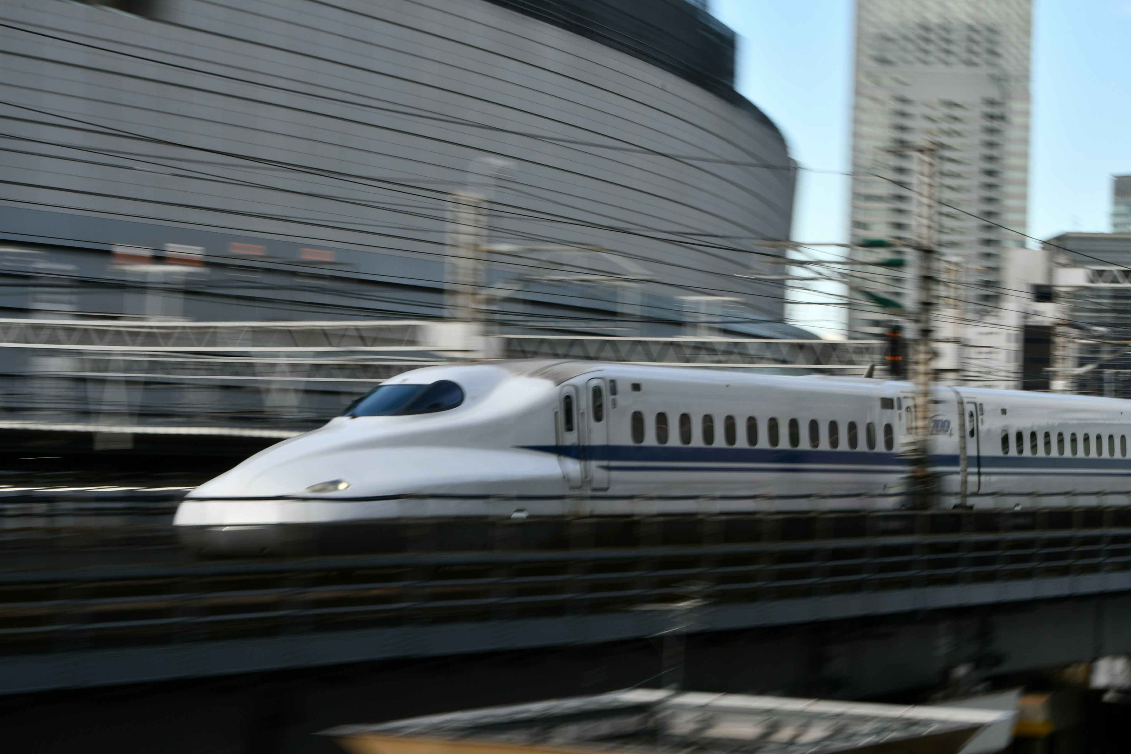 Shinkansen acelerando frente a un fondo urbano dinámico