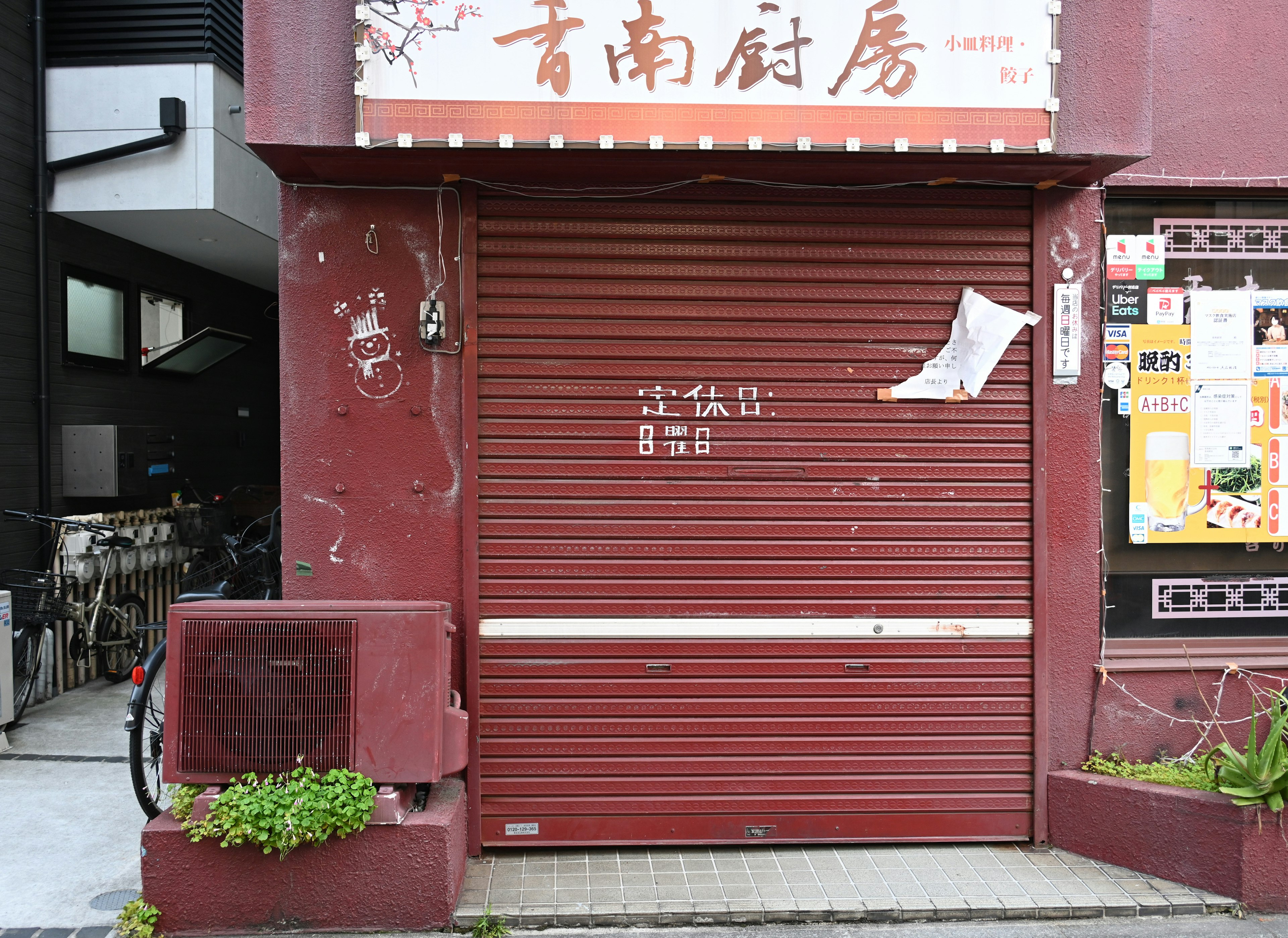 Closed maroon roller shutter of a shop with bicycles nearby