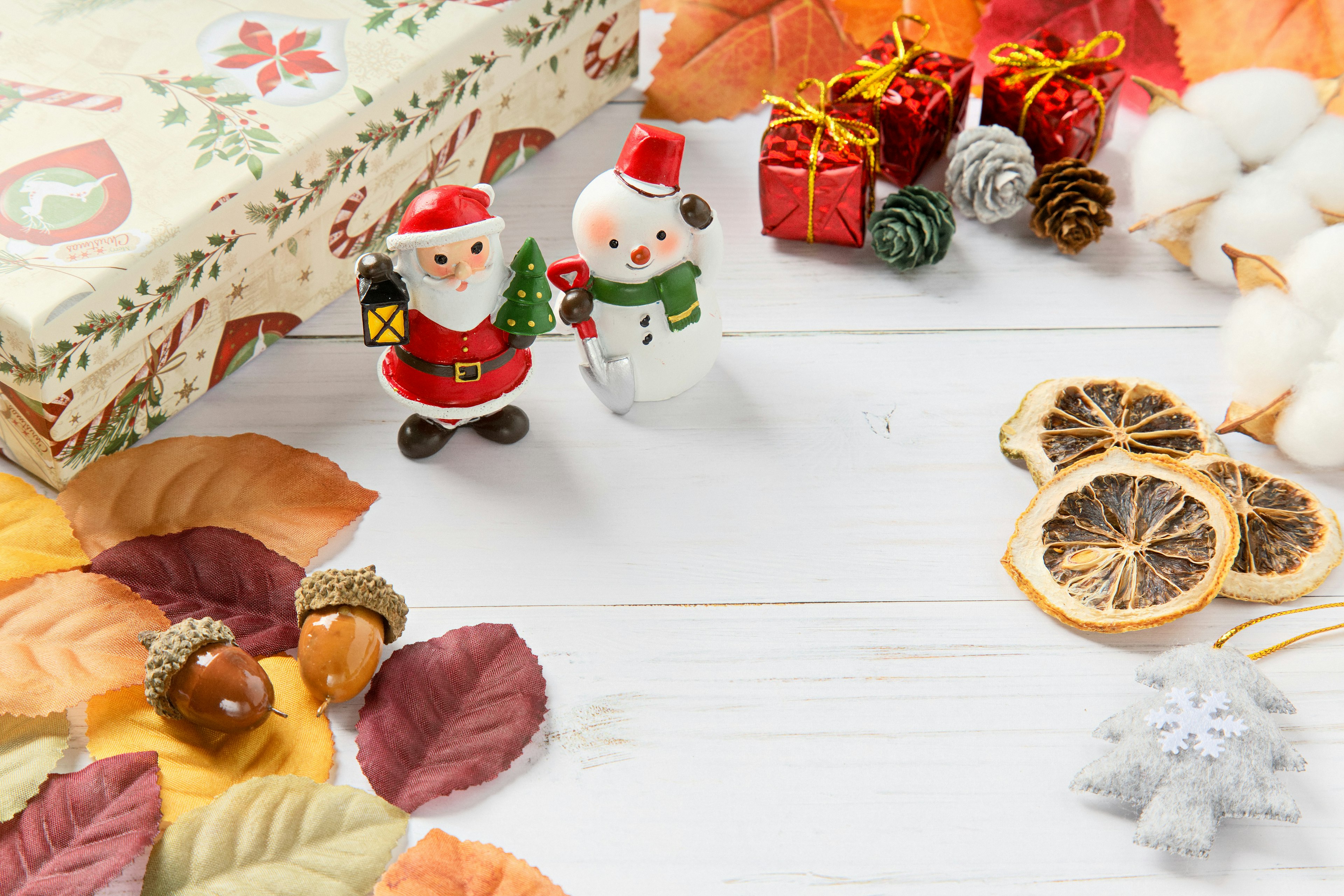 Colorful Christmas decorations featuring Santa and snowman figurines with gifts and autumn leaves