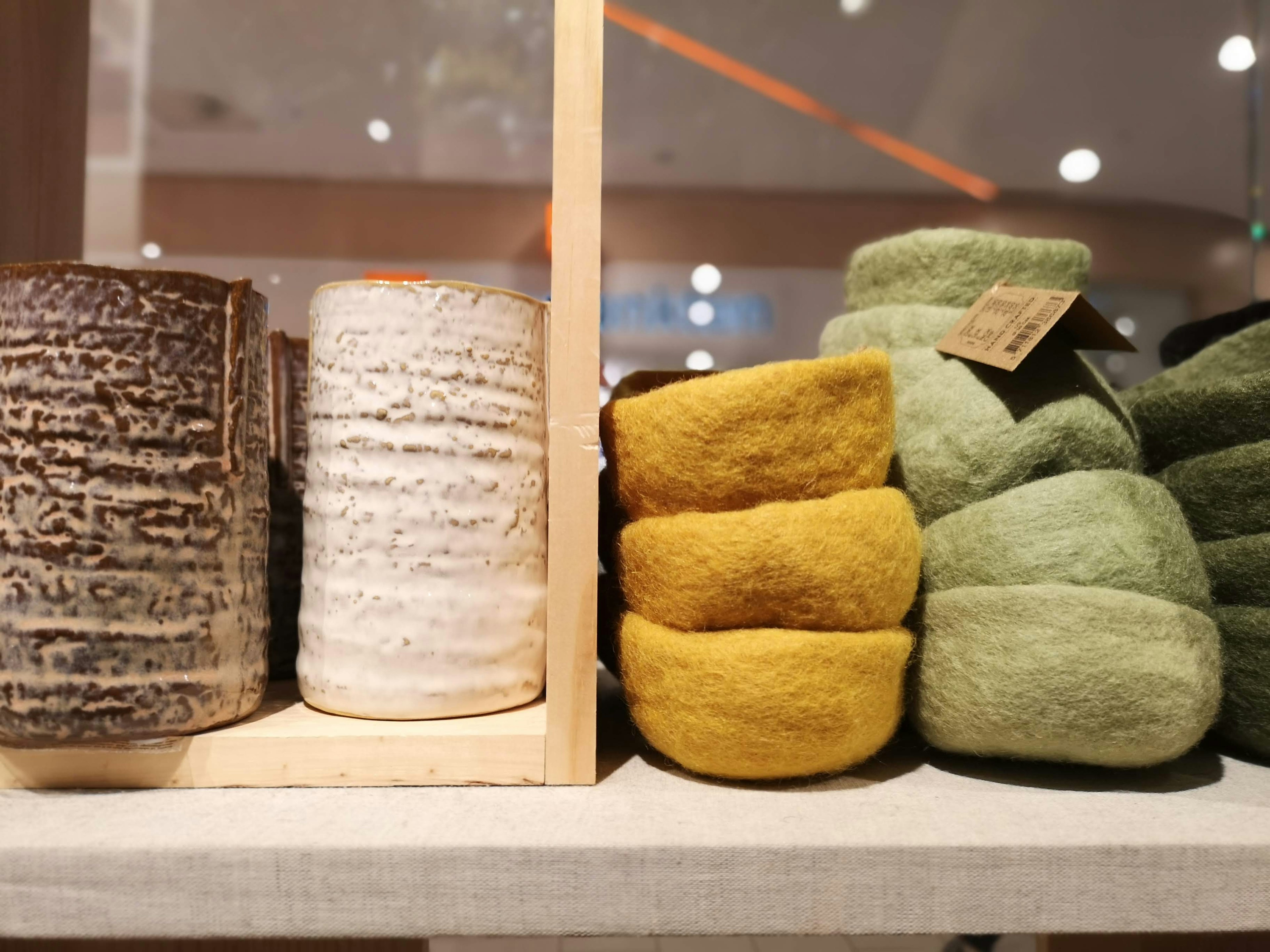 Display of various colored felt bowls and ceramic containers in a store