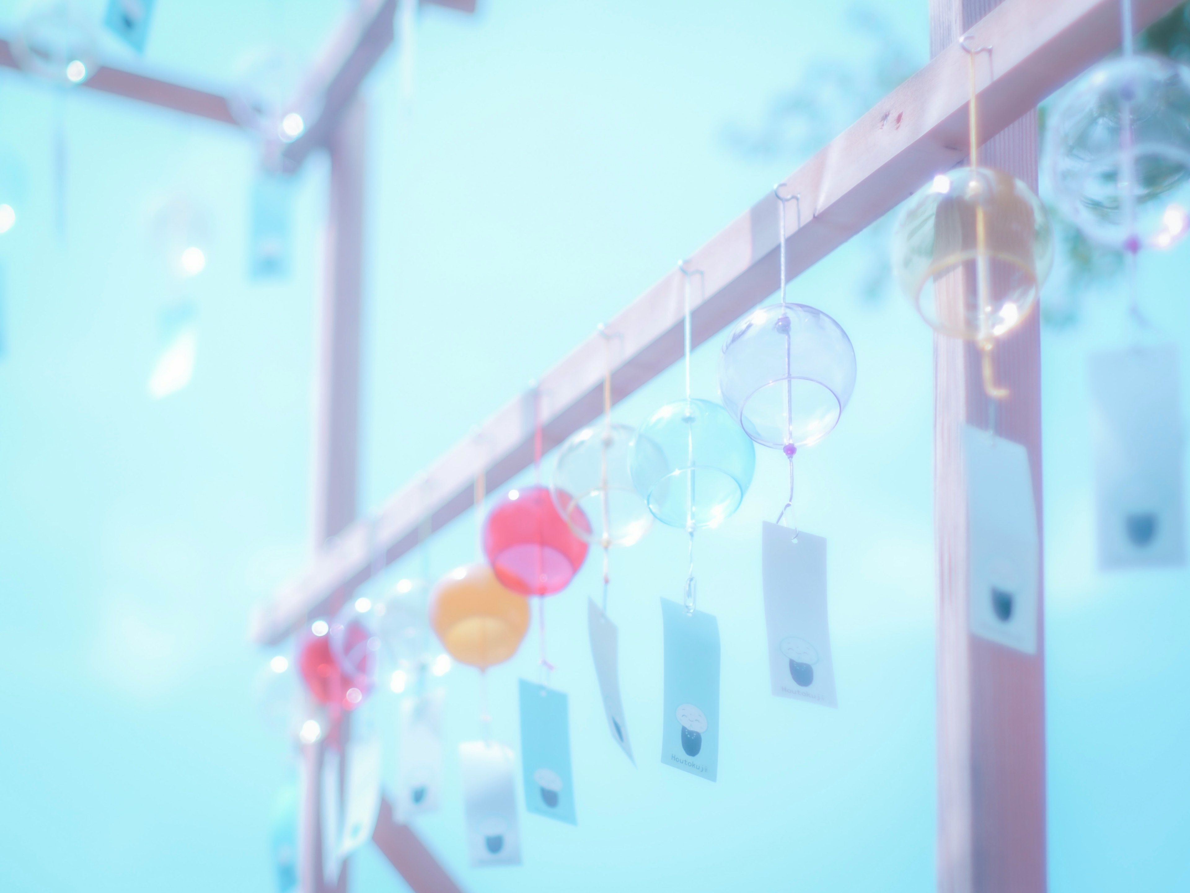 Wind chimes and note cards hanging under a blue sky