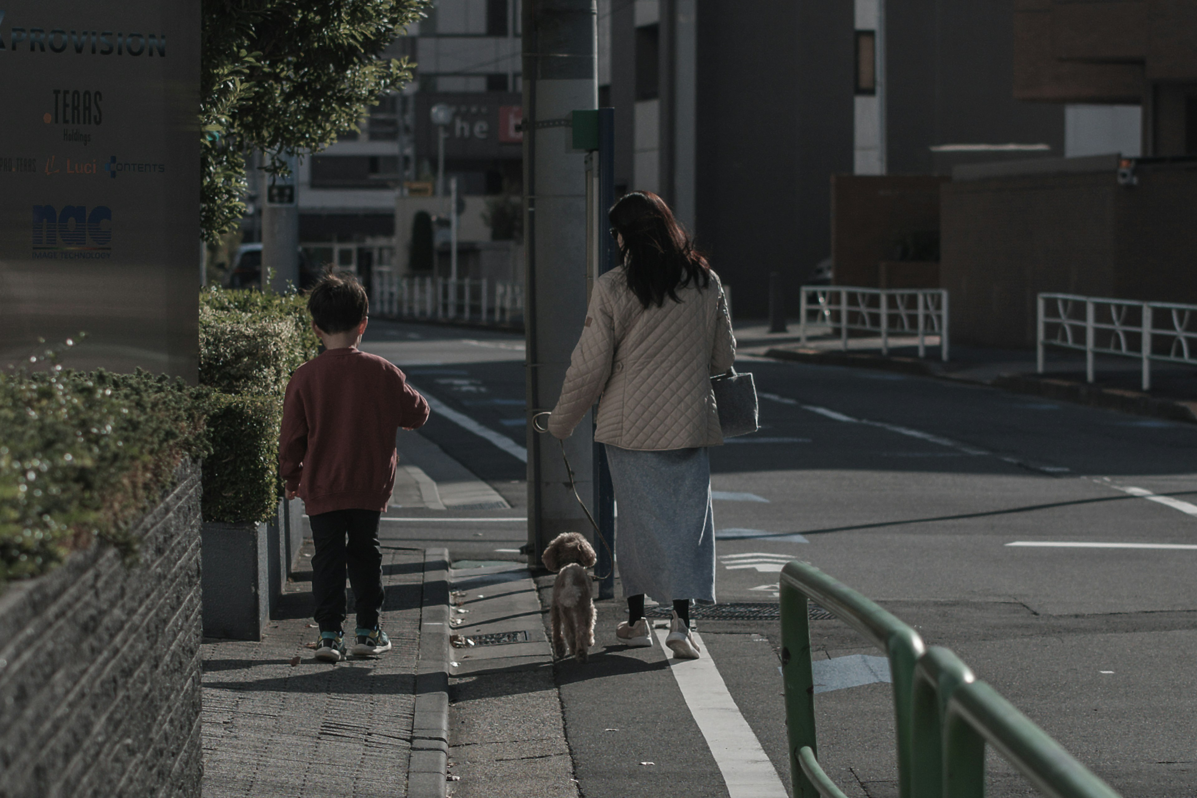 A mother and child walking a dog in an urban setting