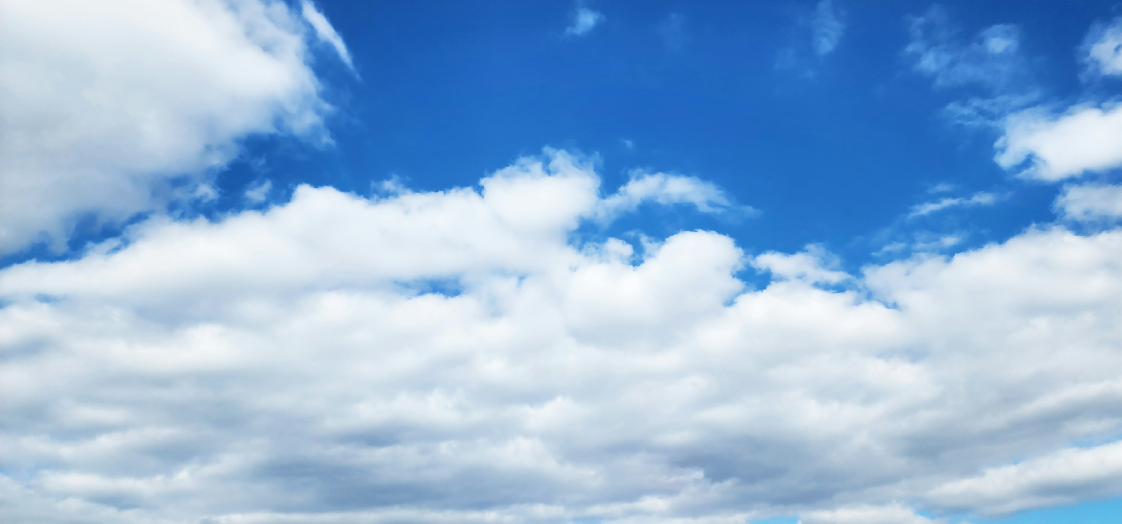 A landscape featuring a blue sky with fluffy white clouds