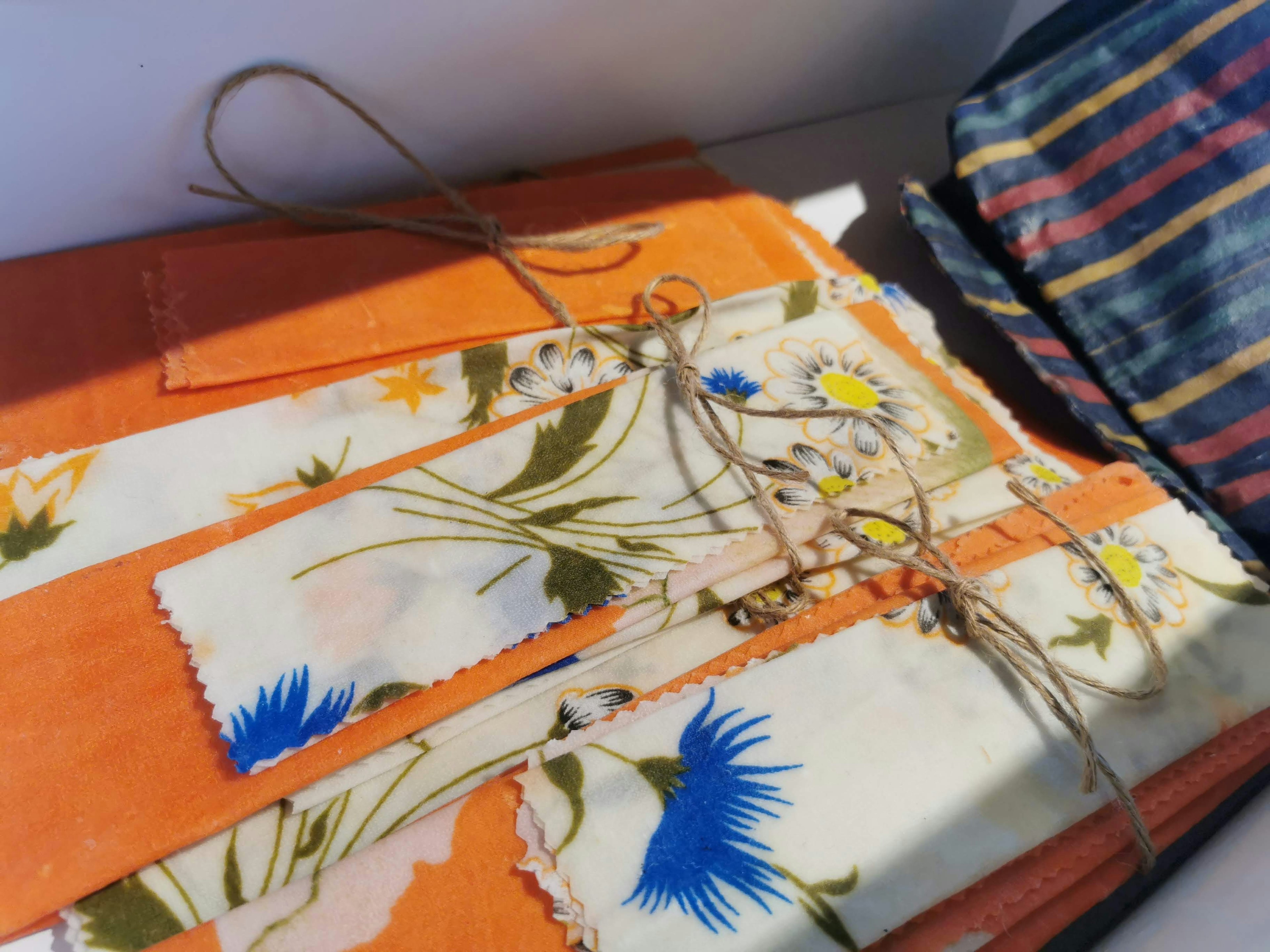 Image of orange fabric with floral patterns and blue flowers layered together