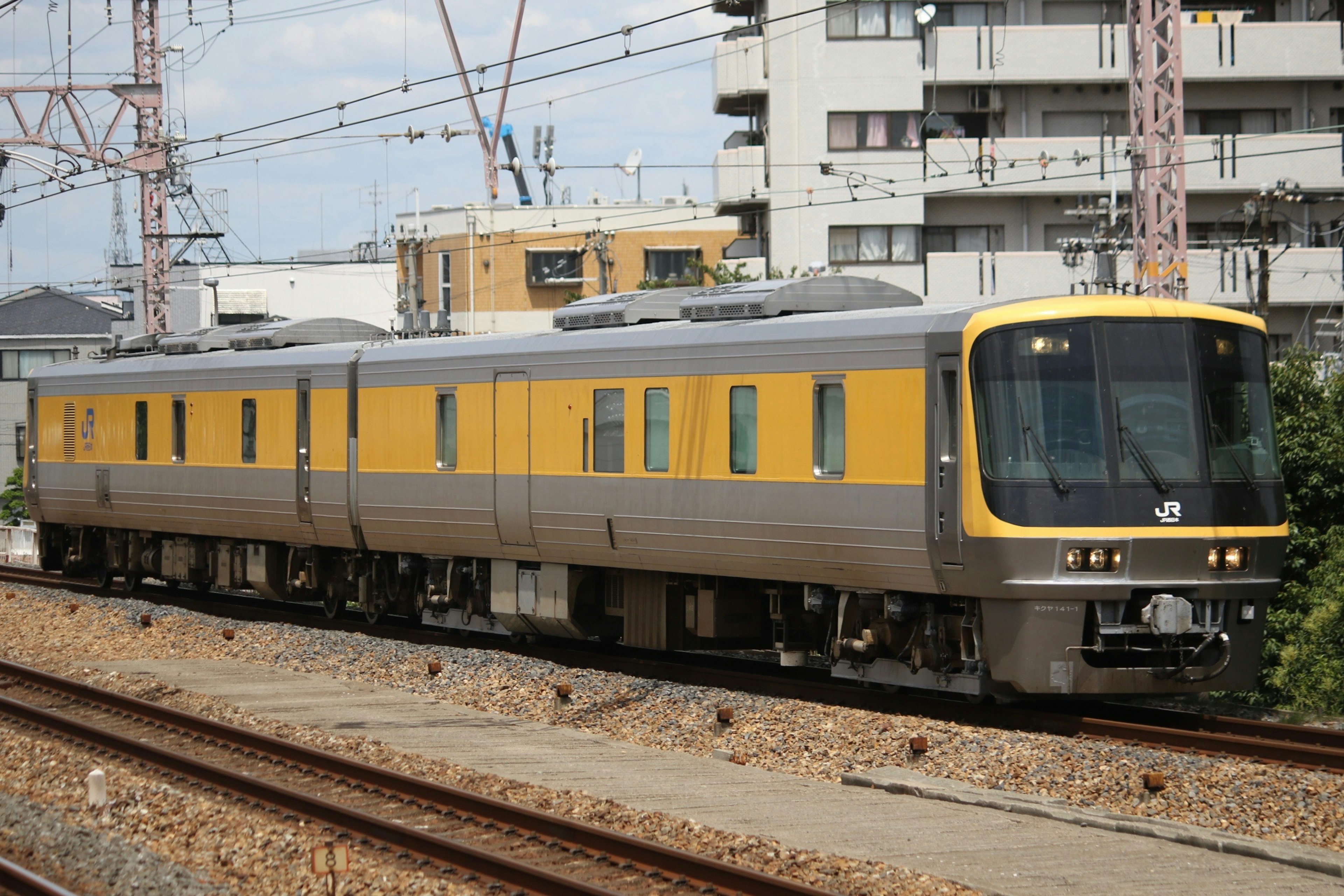 黄色と灰色の電車が線路を走る風景