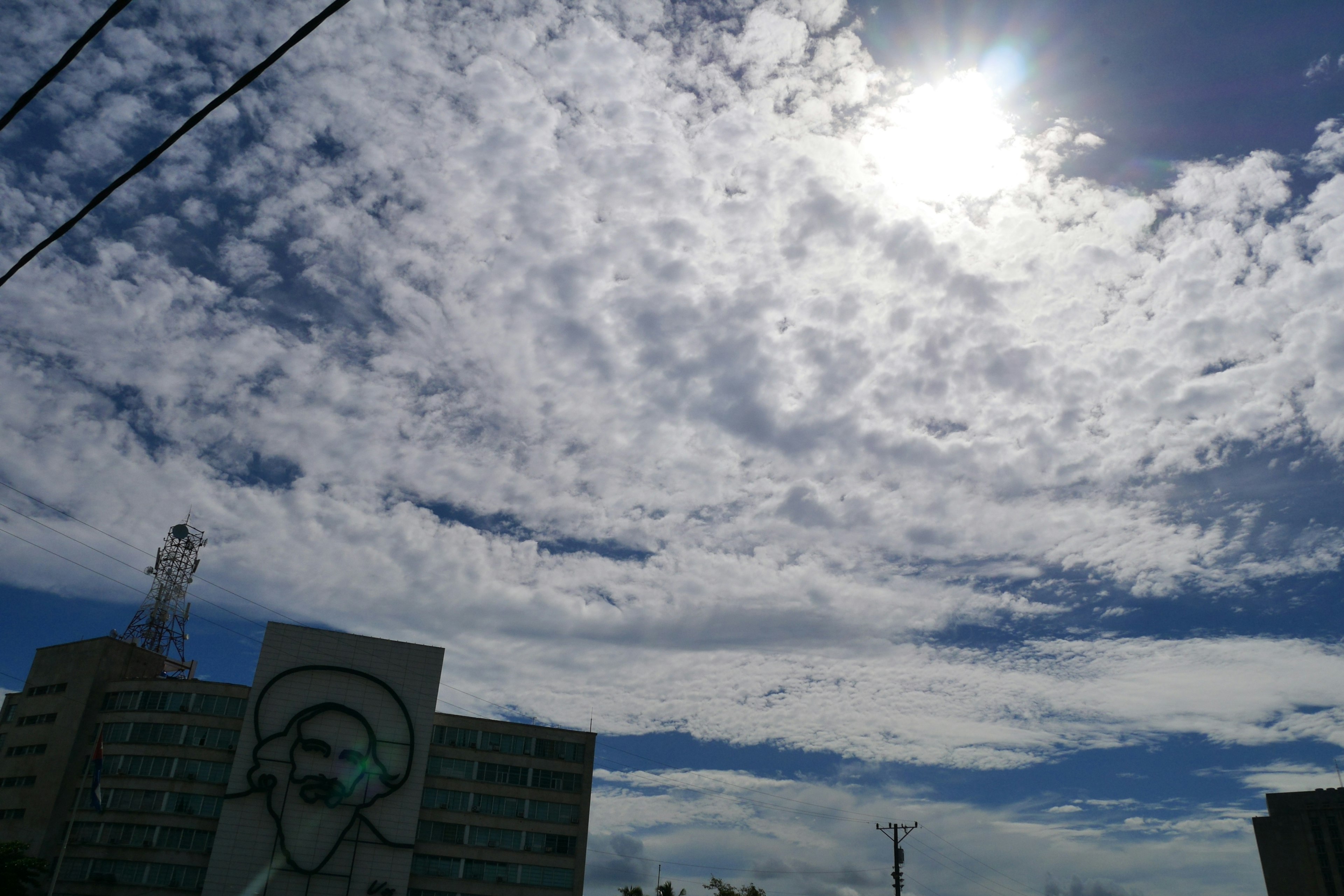 Una vista del cielo azul con nubes blancas y sol brillante graffiti en la pared de un edificio alto