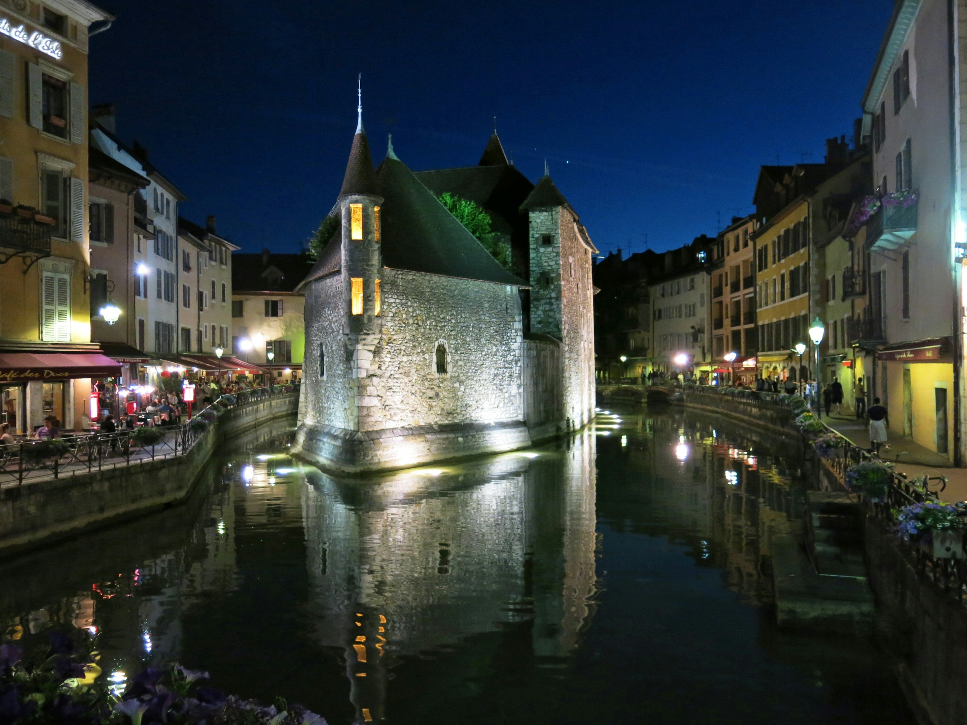 Bellissima scena notturna di Annecy con un edificio in pietra e acqua calma