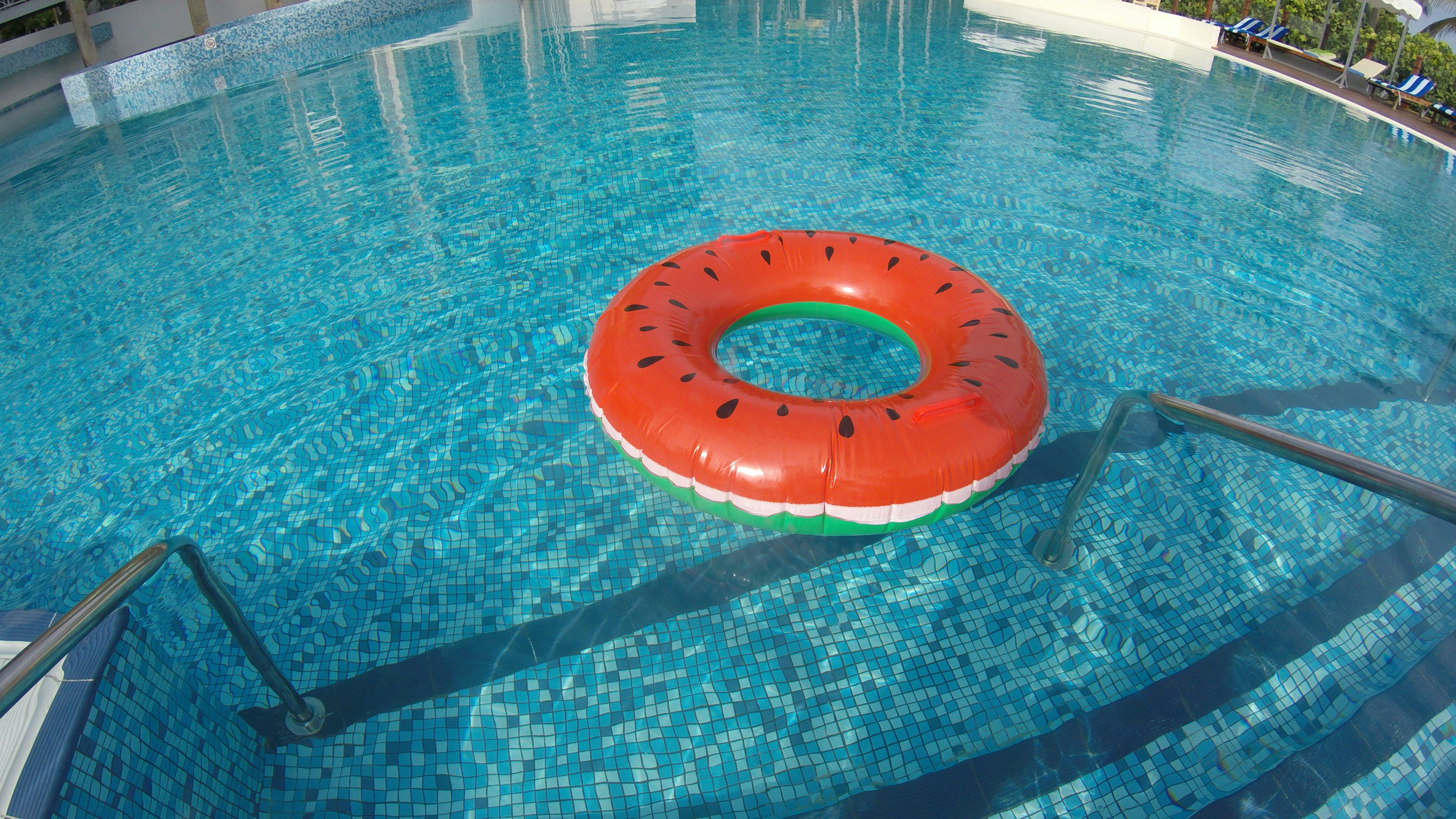 Flotador con forma de sandía en una piscina con azulejos azules