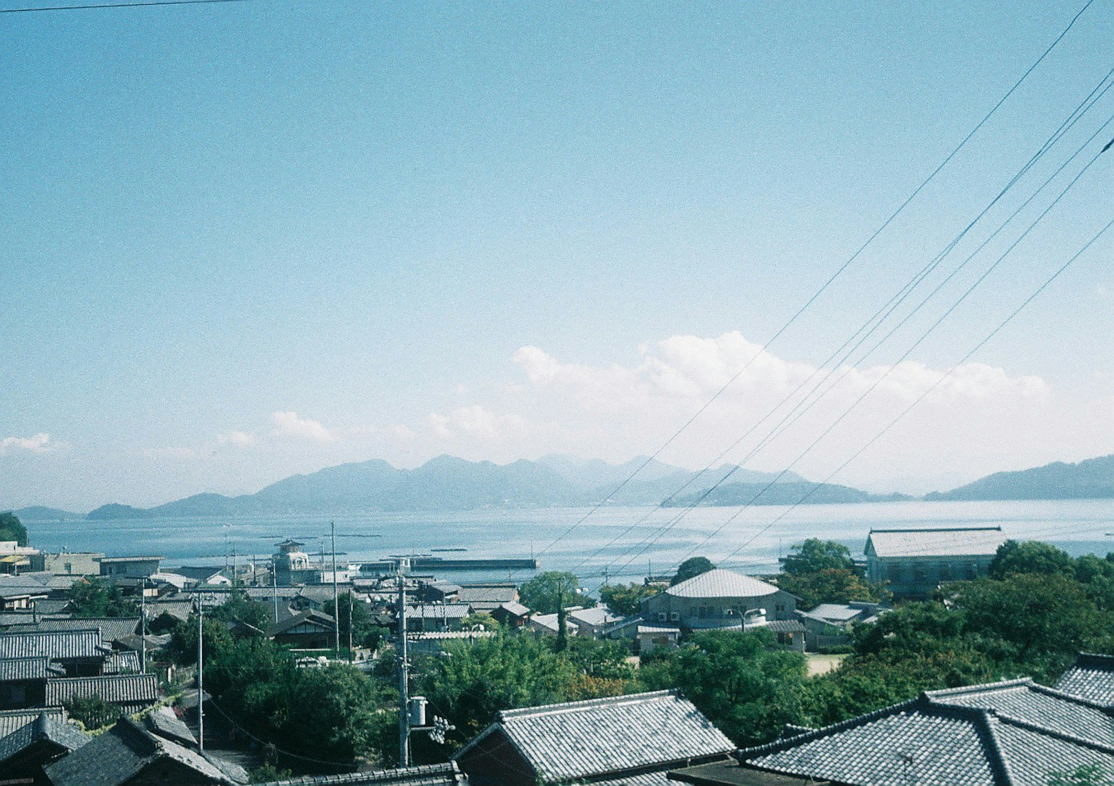 Seaside view with traditional houses against a backdrop of mountains and clear blue sky