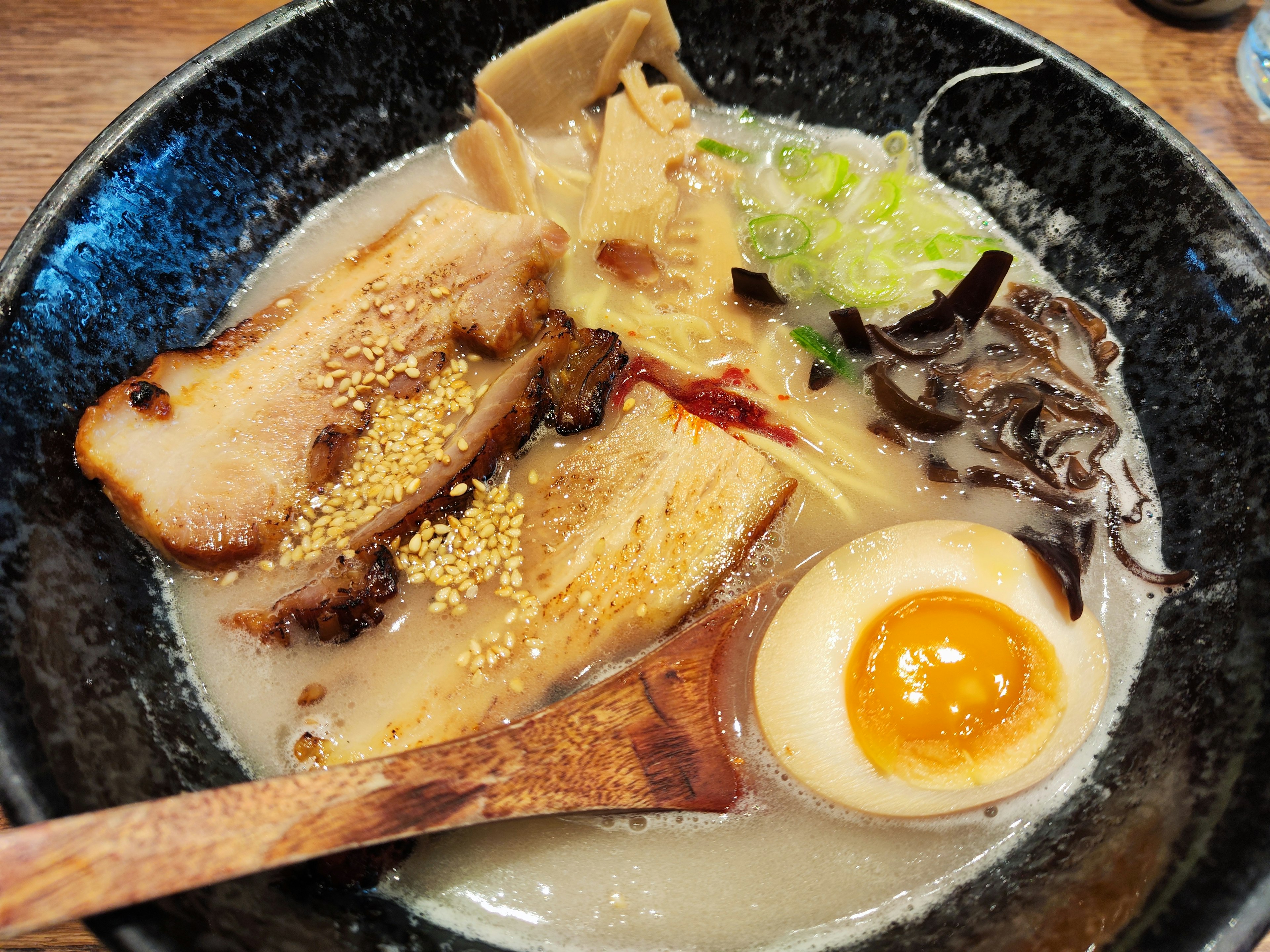 Sebuah mangkuk ramen tonkotsu kaya dengan chashu, telur rebus, menma, bawang hijau, dan nori