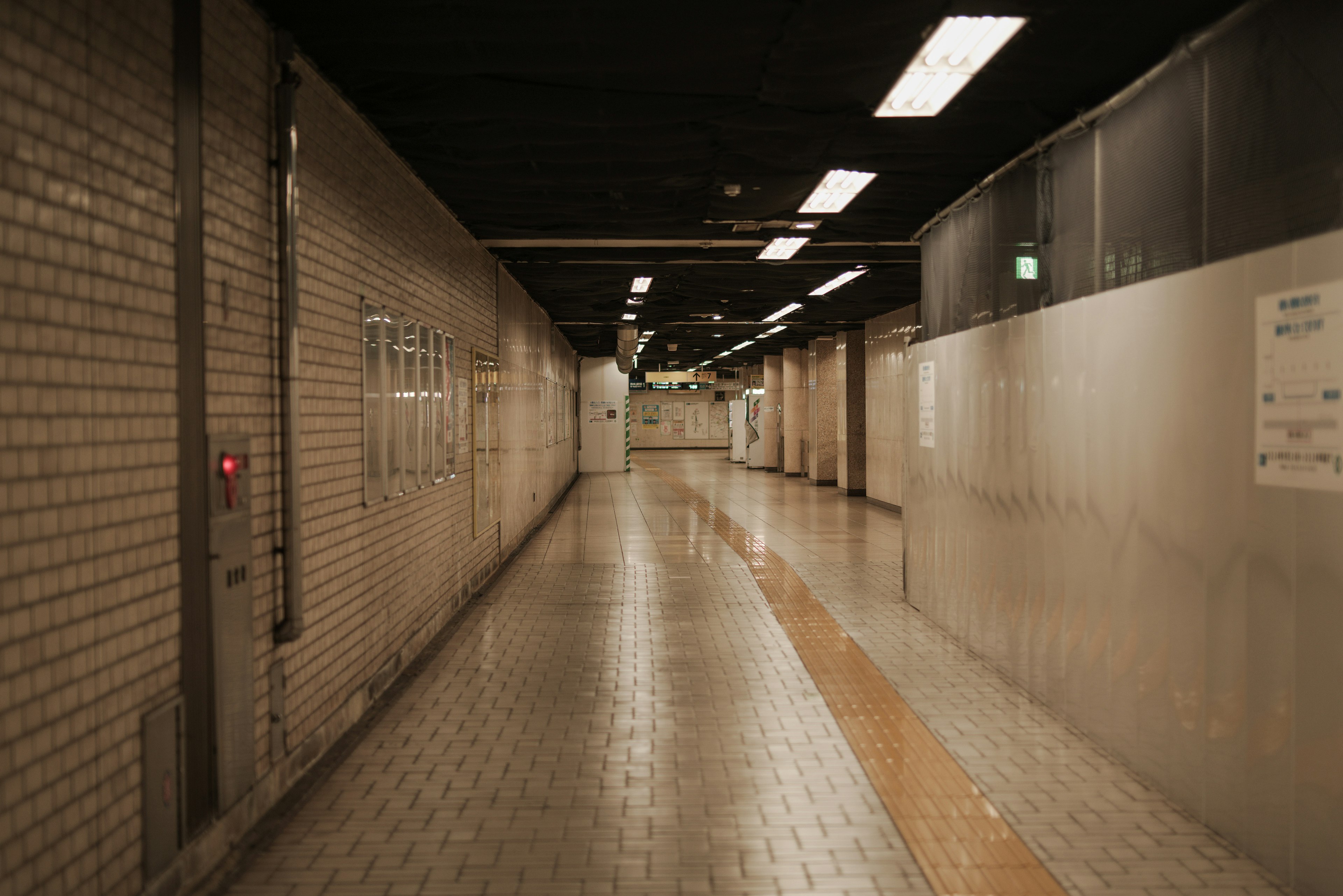 Largo corredor en un paso subterráneo con iluminación brillante y suelo de azulejos