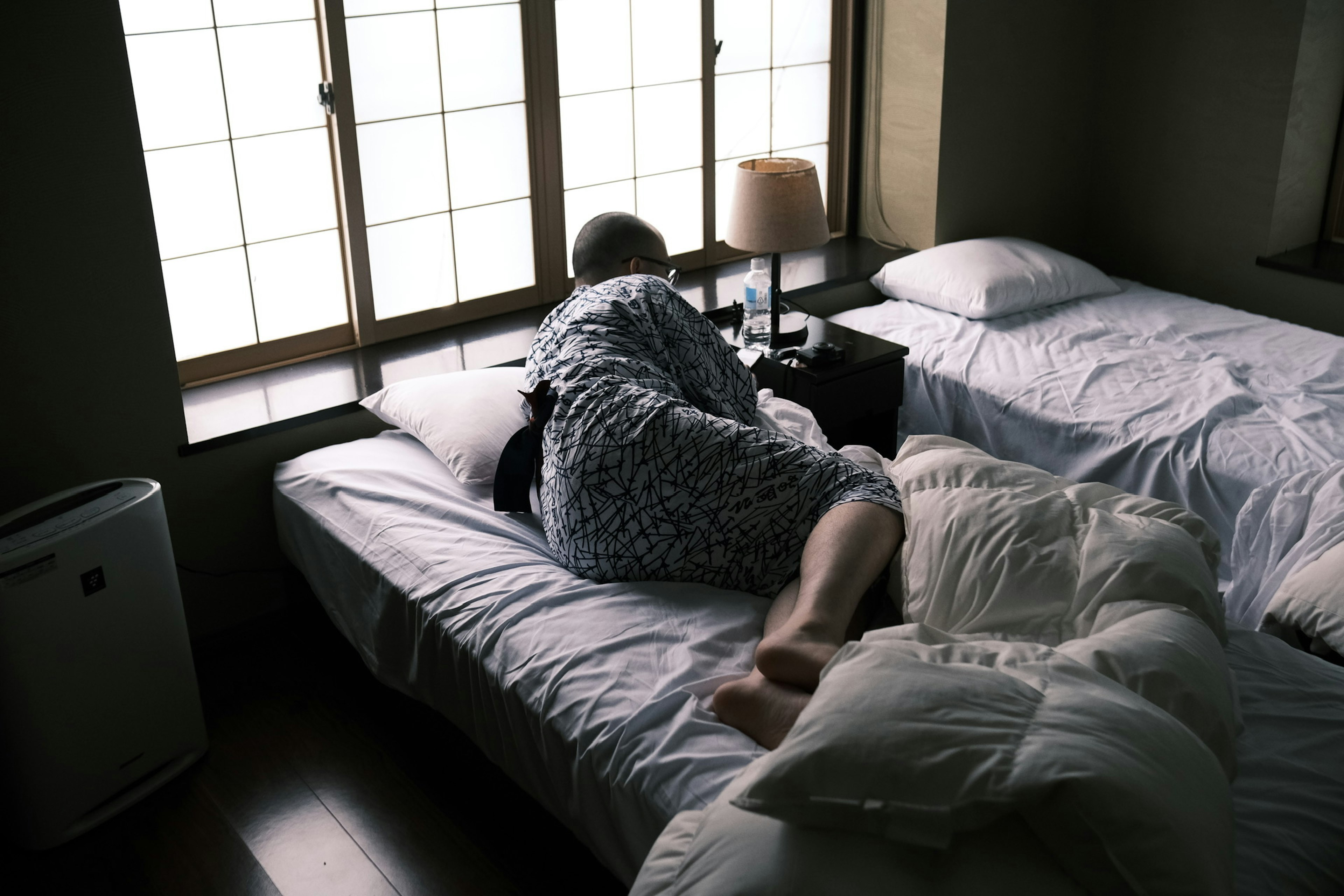 Una persona acostada en una cama en un dormitorio Luz suave que entra por la ventana con un interior sencillo