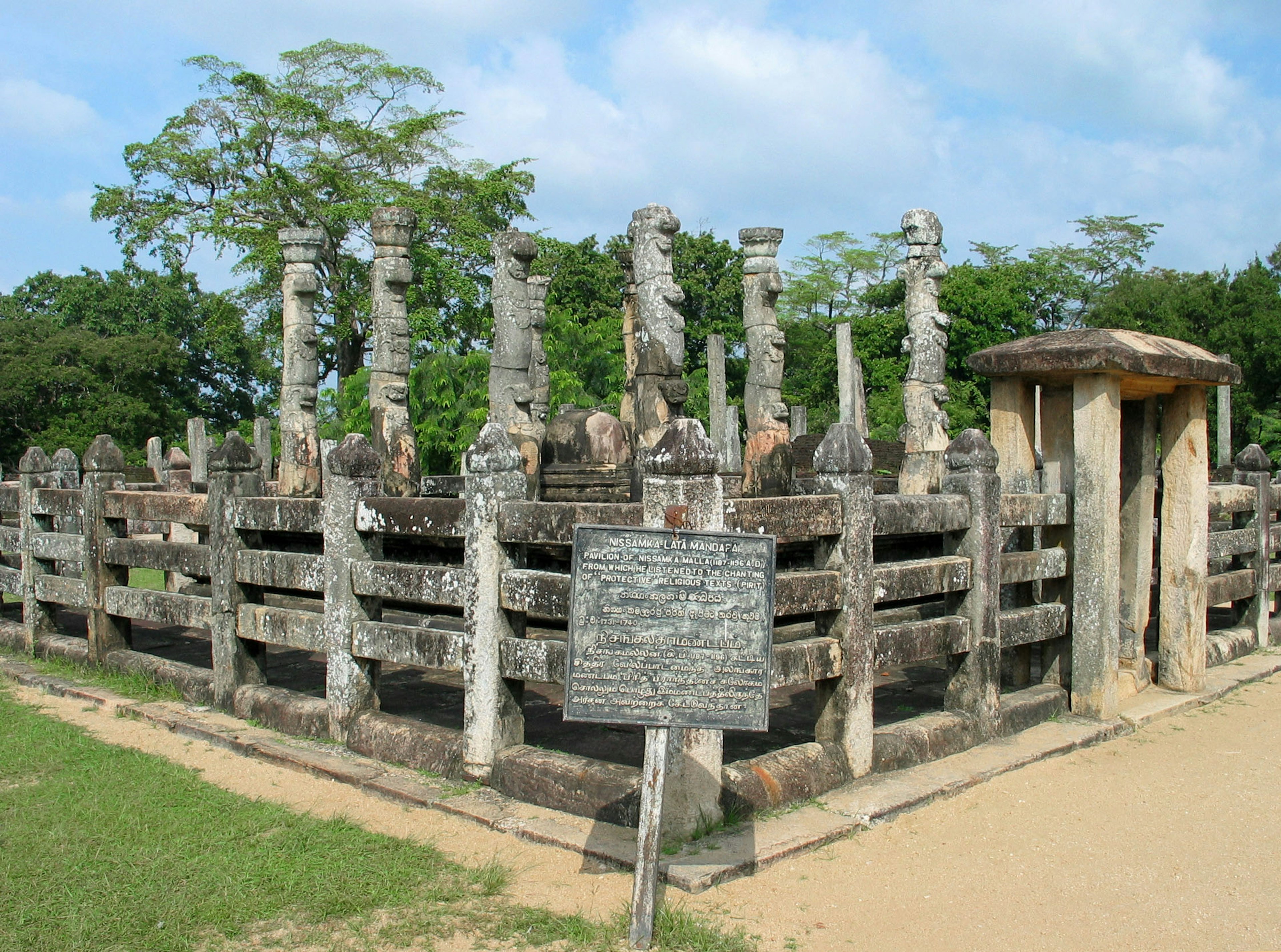 Ancient stone pillars surrounding a historical site with an information board