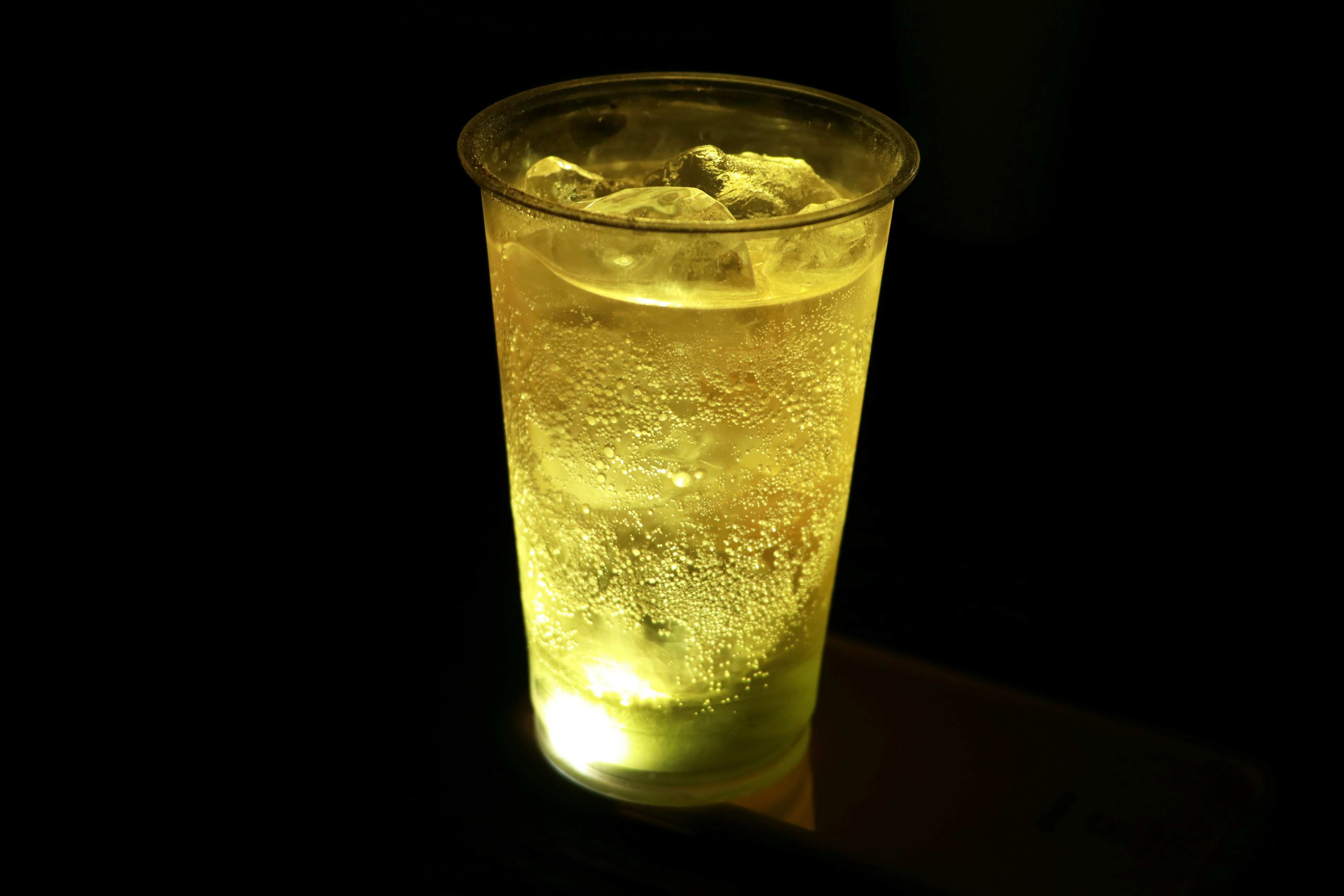 Boisson jaune lumineuse dans un gobelet sur fond sombre