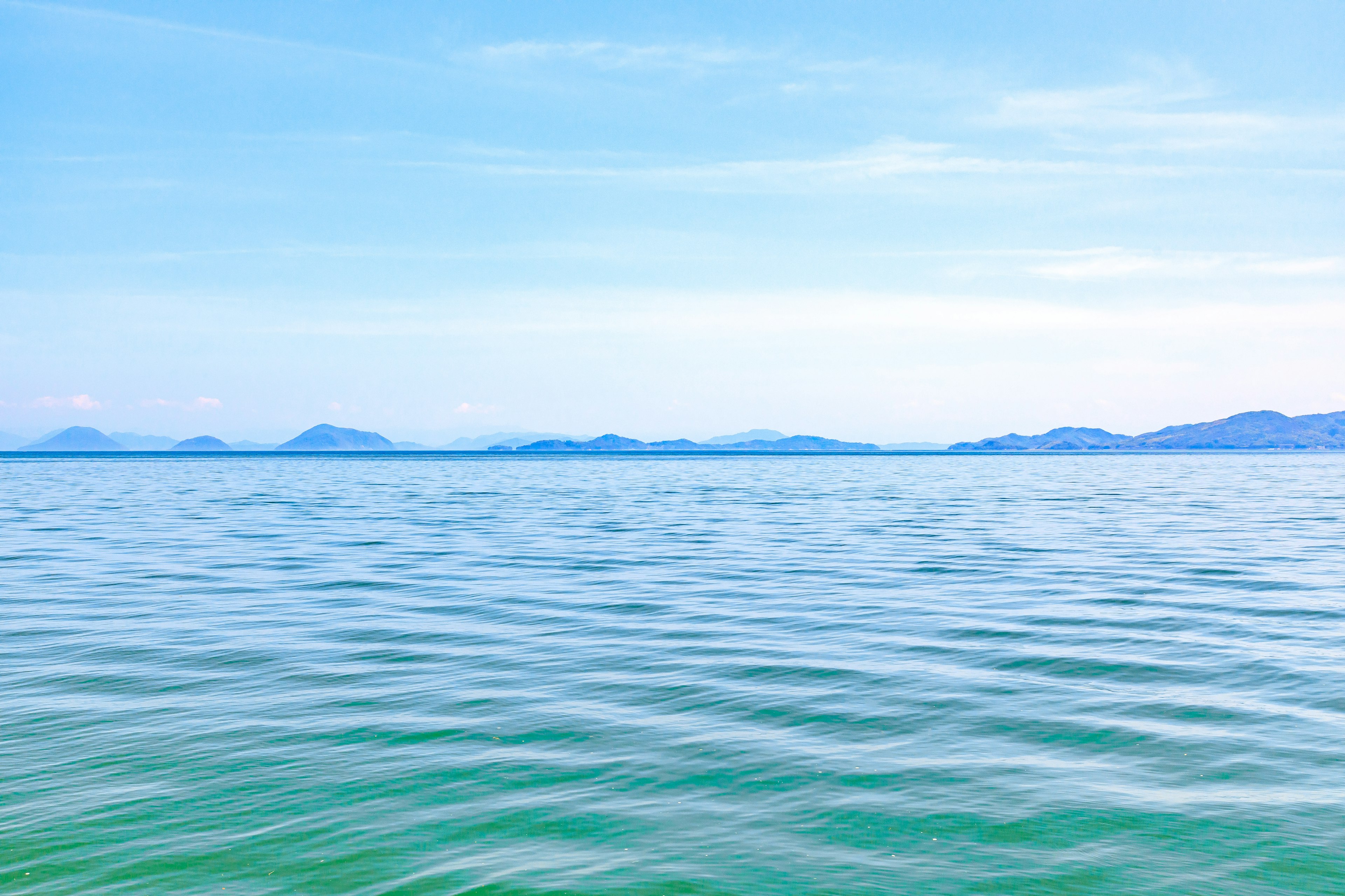 Un paysage serein avec une mer et un ciel bleus présentant des ondulations sur l'eau