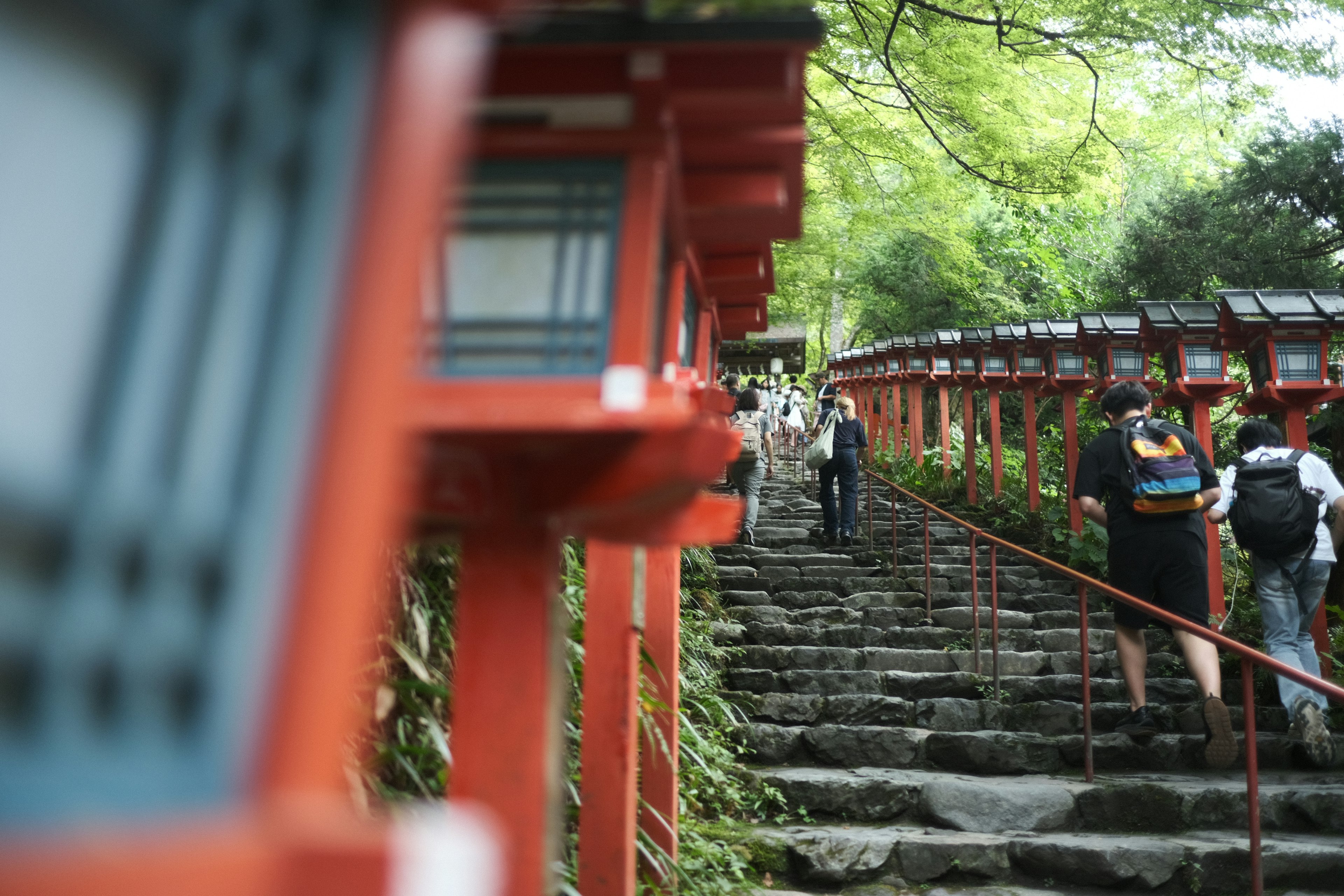 Scene of red torii gates and stone steps with people walking