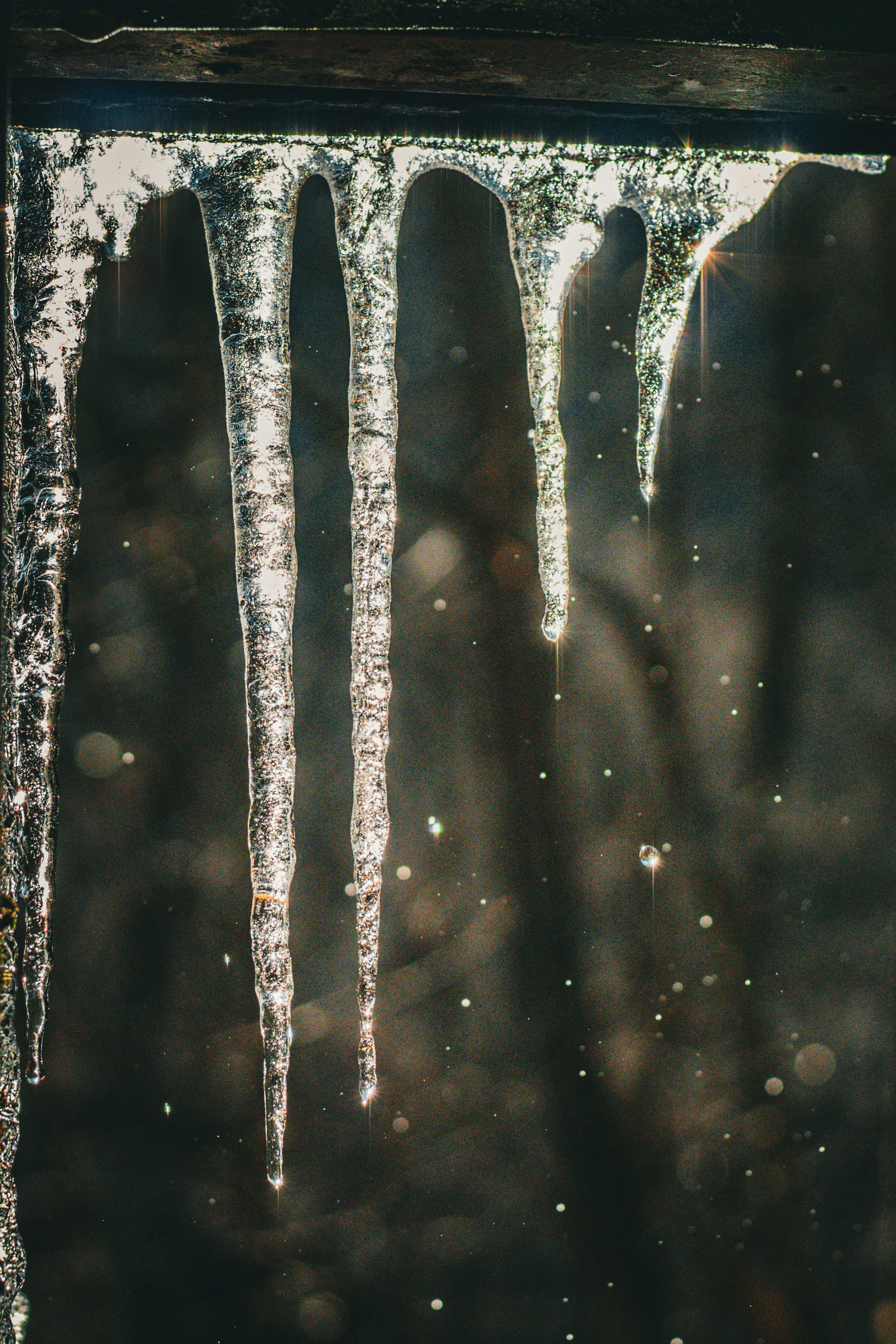 Eiszapfen hängen in der Nähe eines Fensters mit verschwommenem Hintergrund