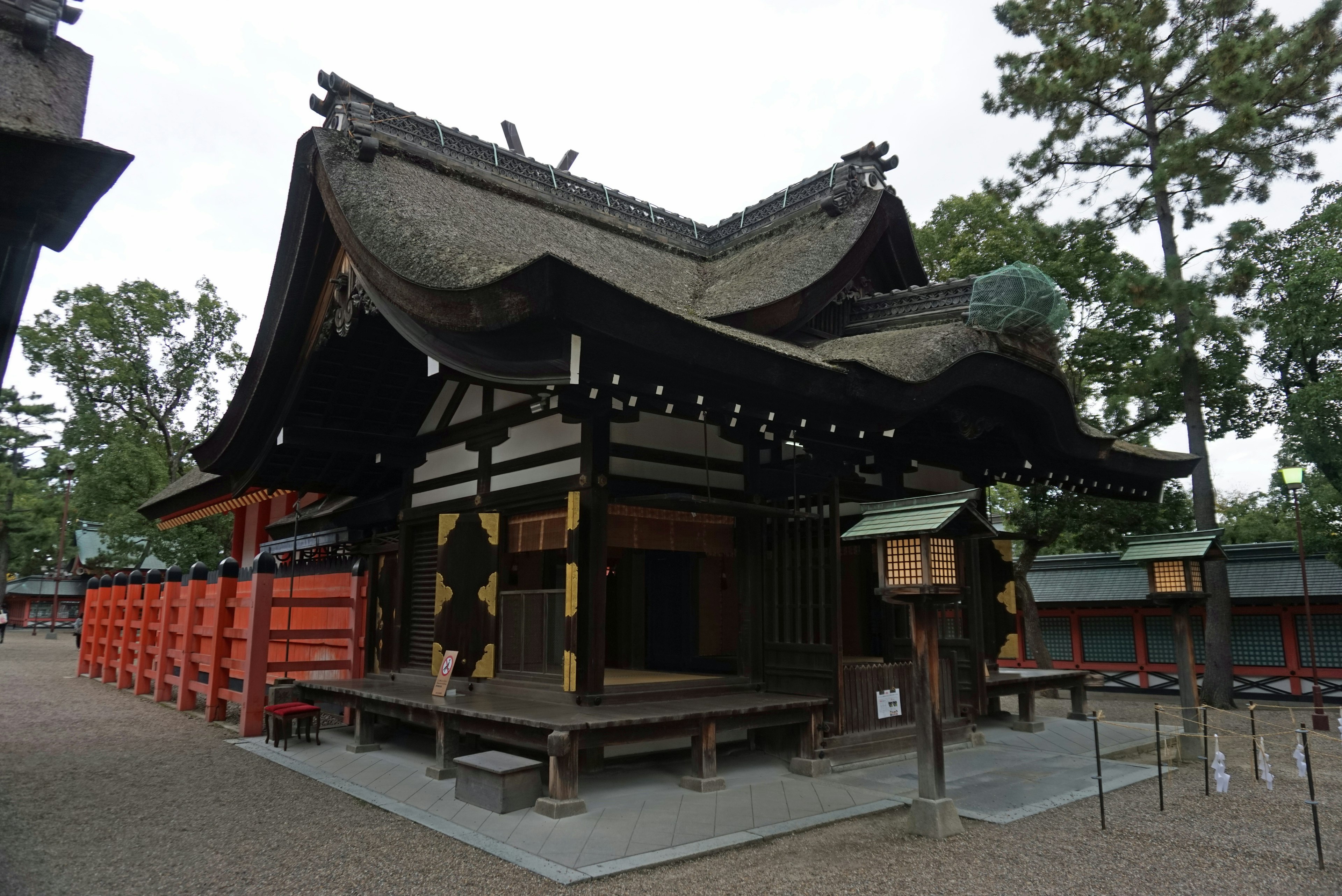 Traditional Japanese shrine building with distinctive curved roof surrounded by green trees