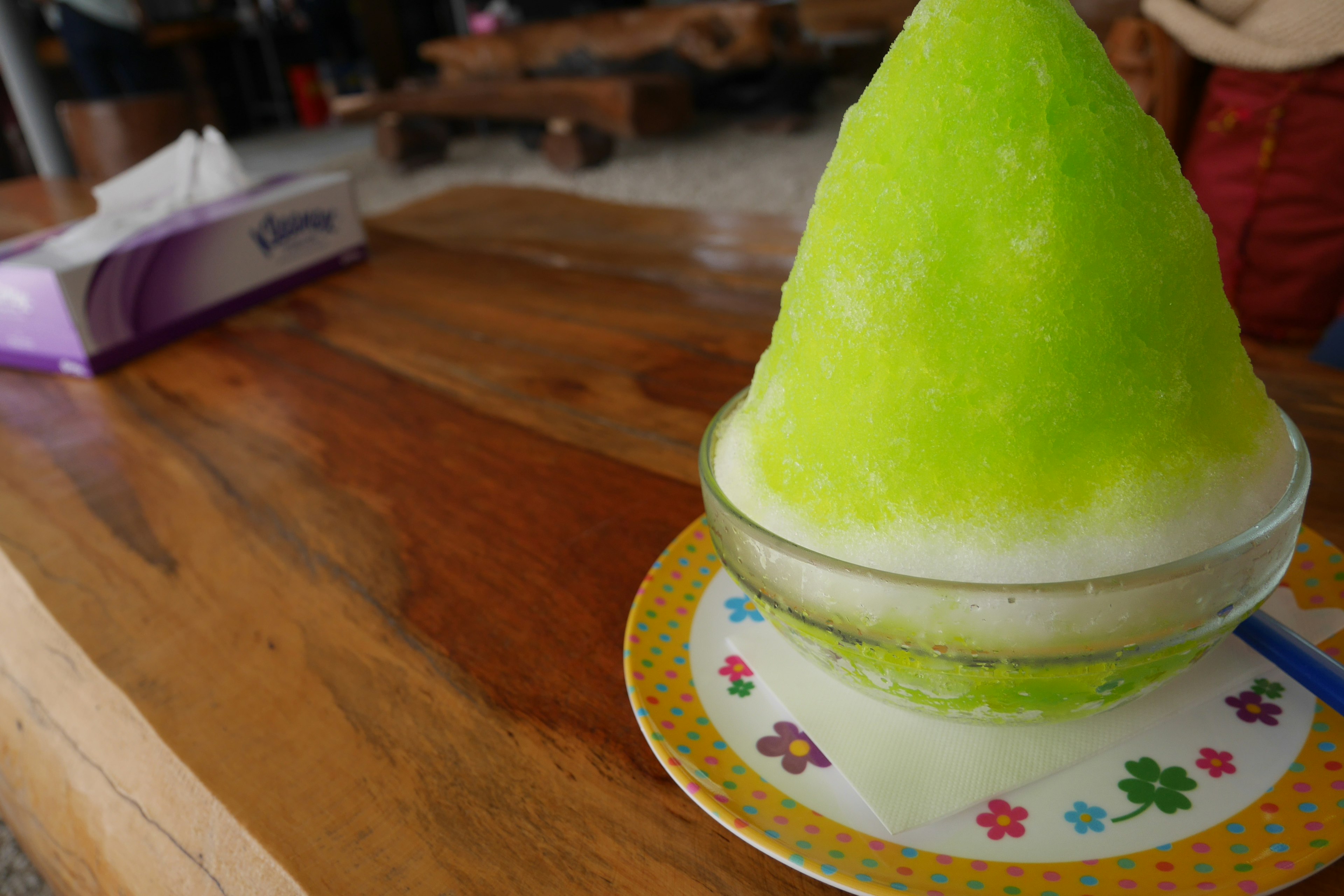 Un glace pilée verte vibrante servie dans un bol sur une table en bois