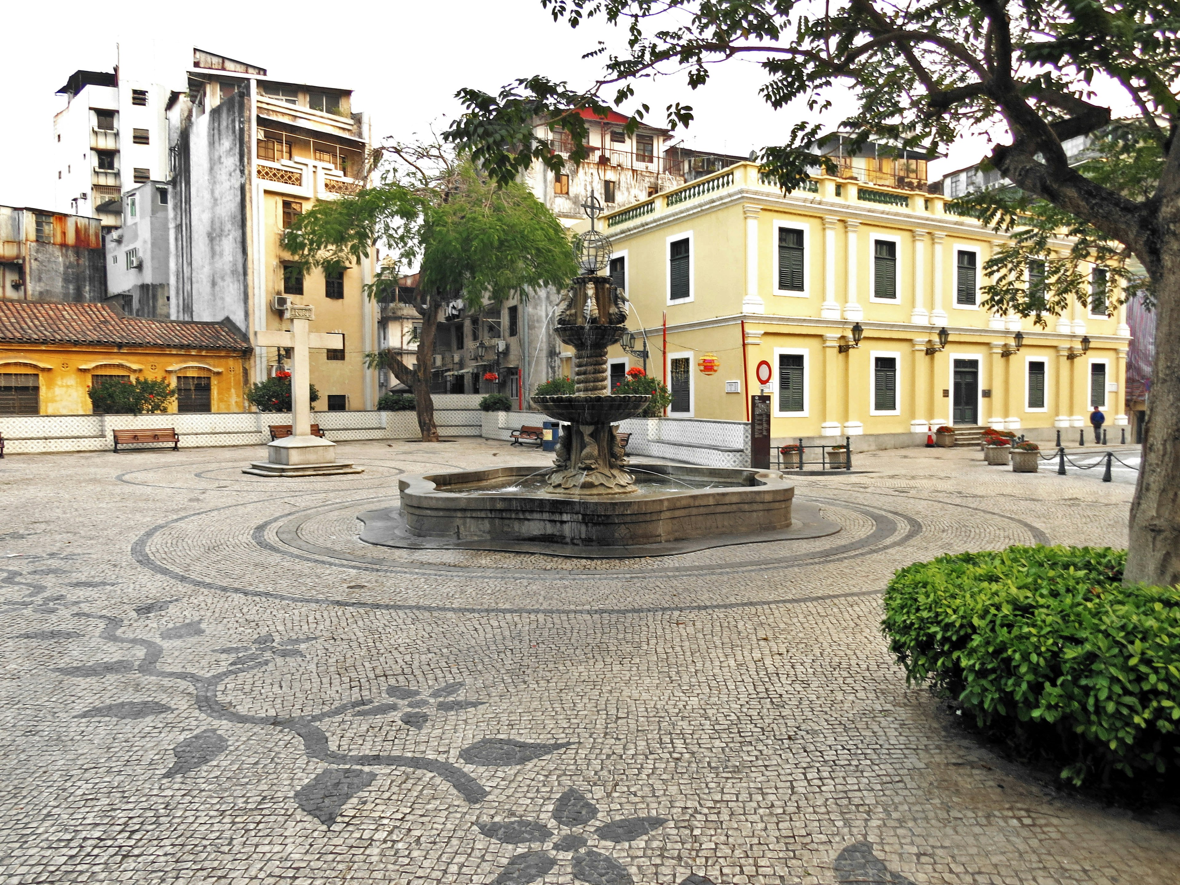 A quiet square featuring a fountain and surrounding buildings