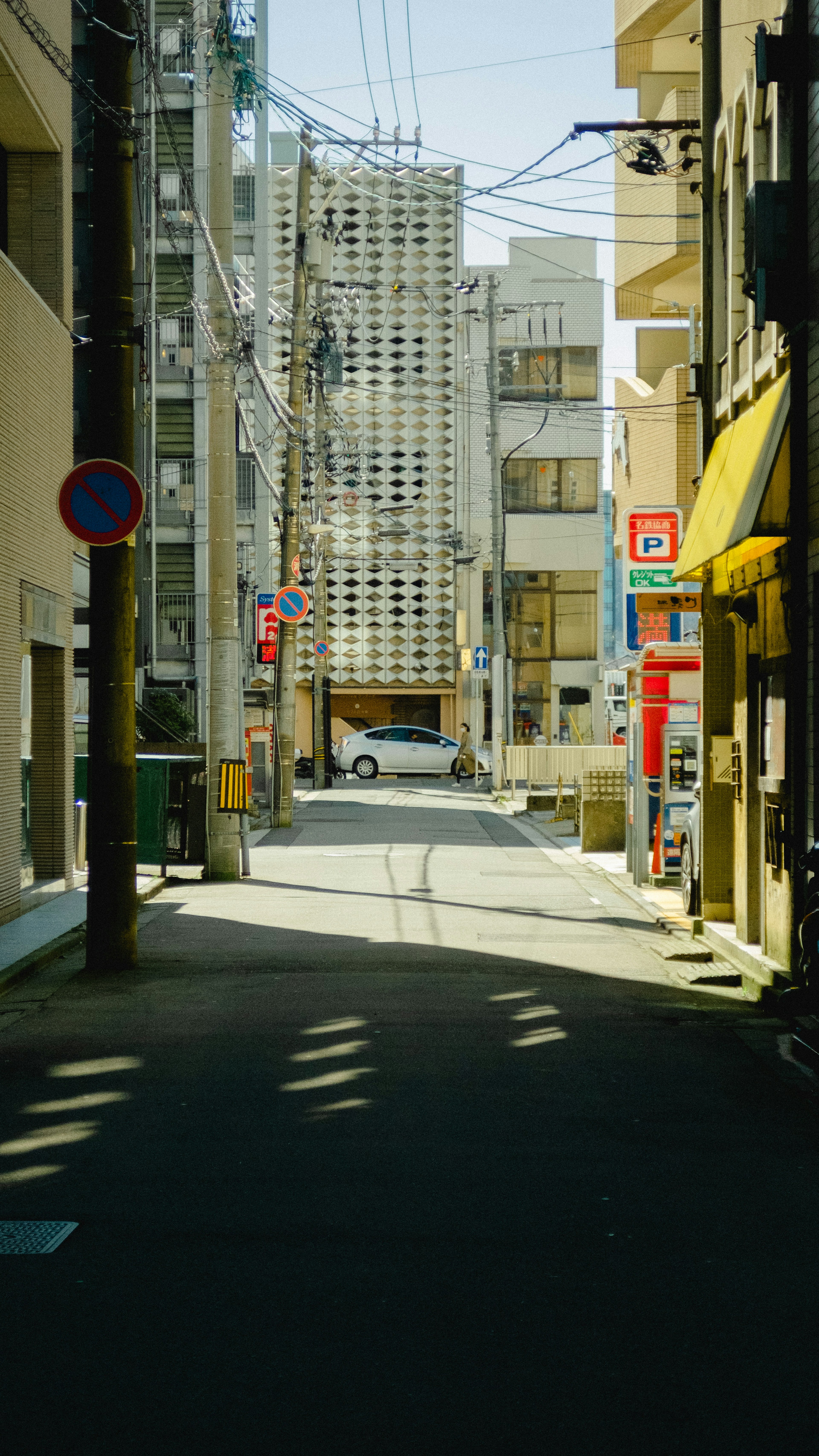 Calle estrecha flanqueada por edificios y sombras