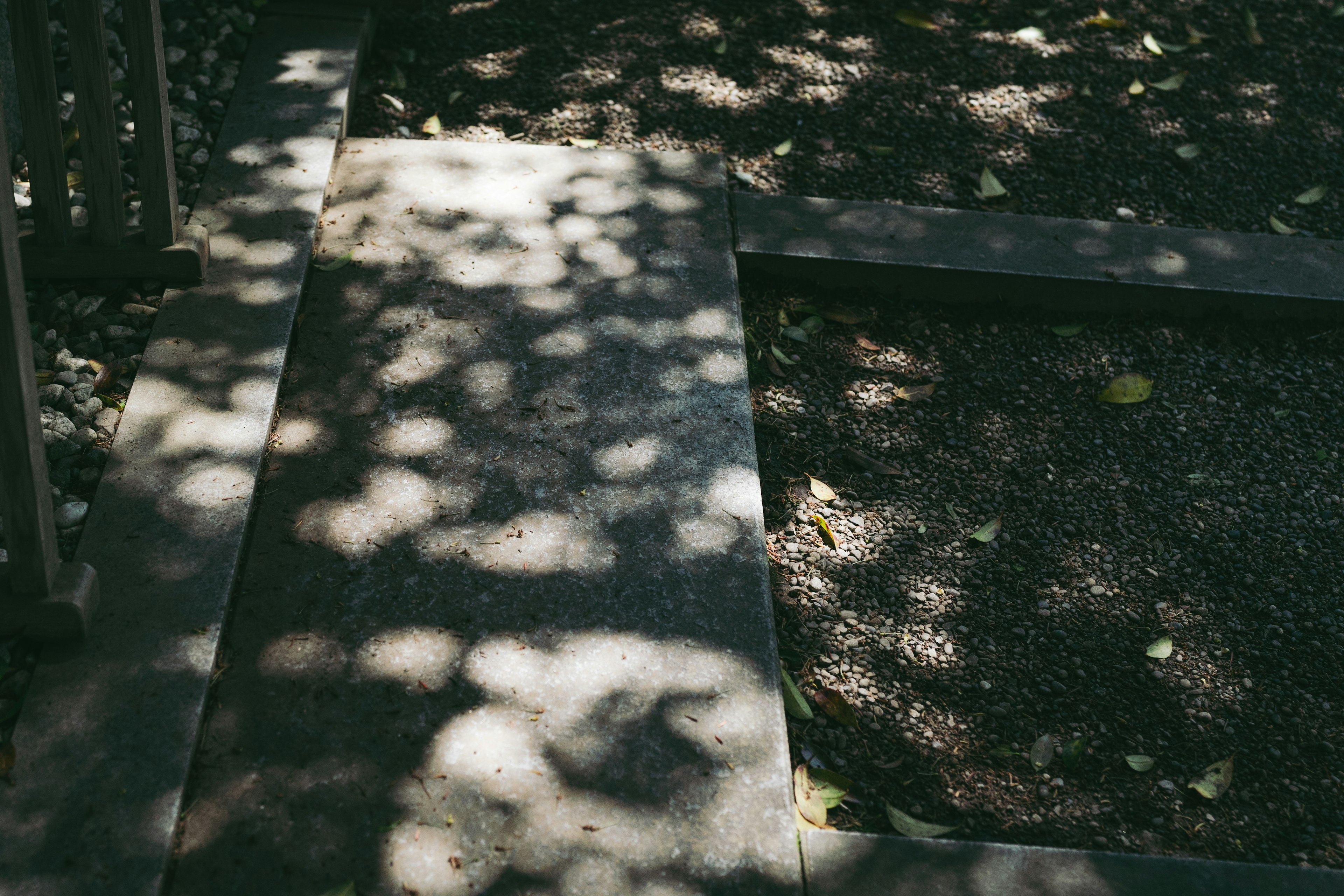 Allée pavée avec des motifs d'ombre et une zone de gravier