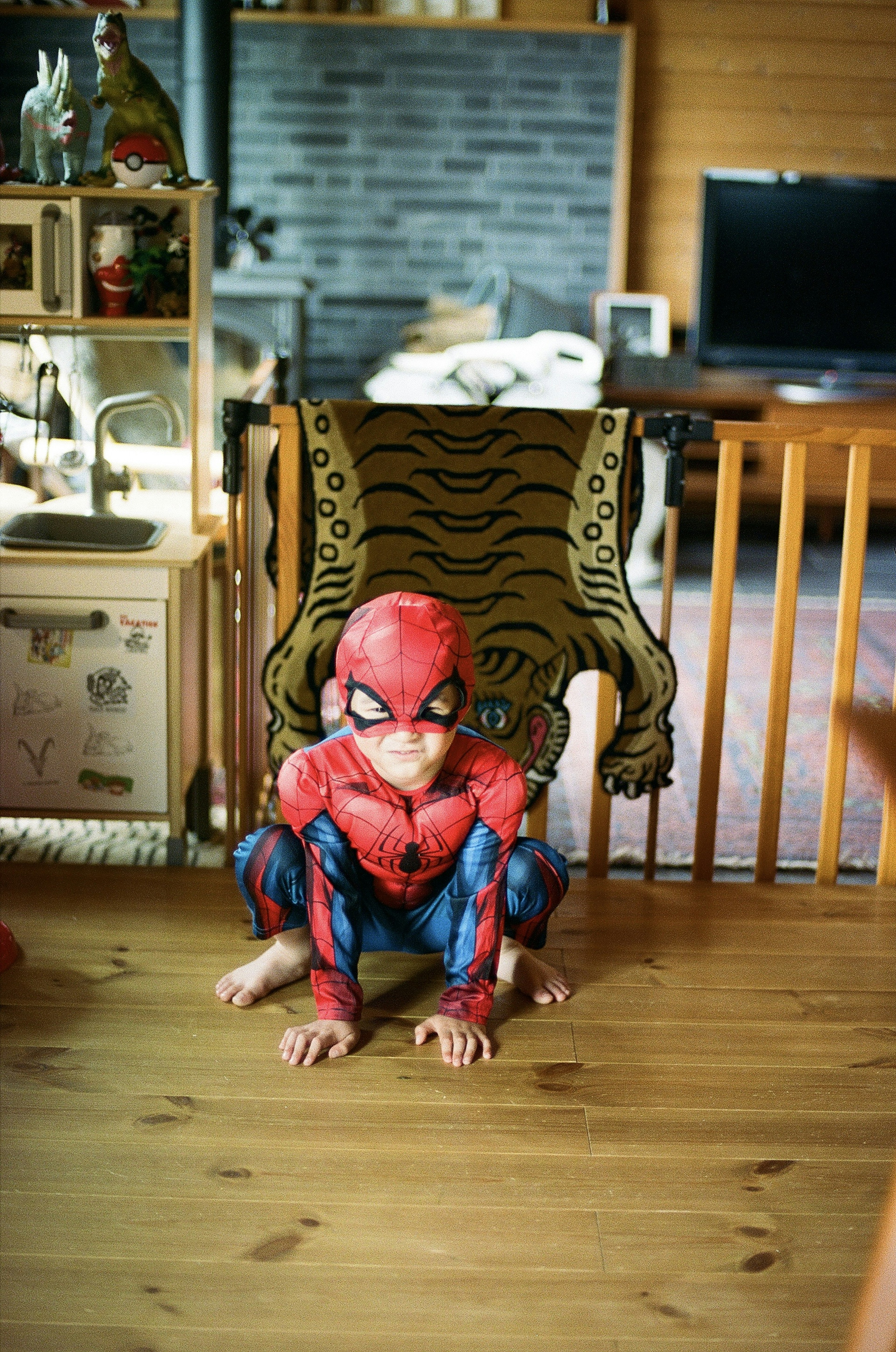 A child in a Spider-Man costume is sitting in front of a chair