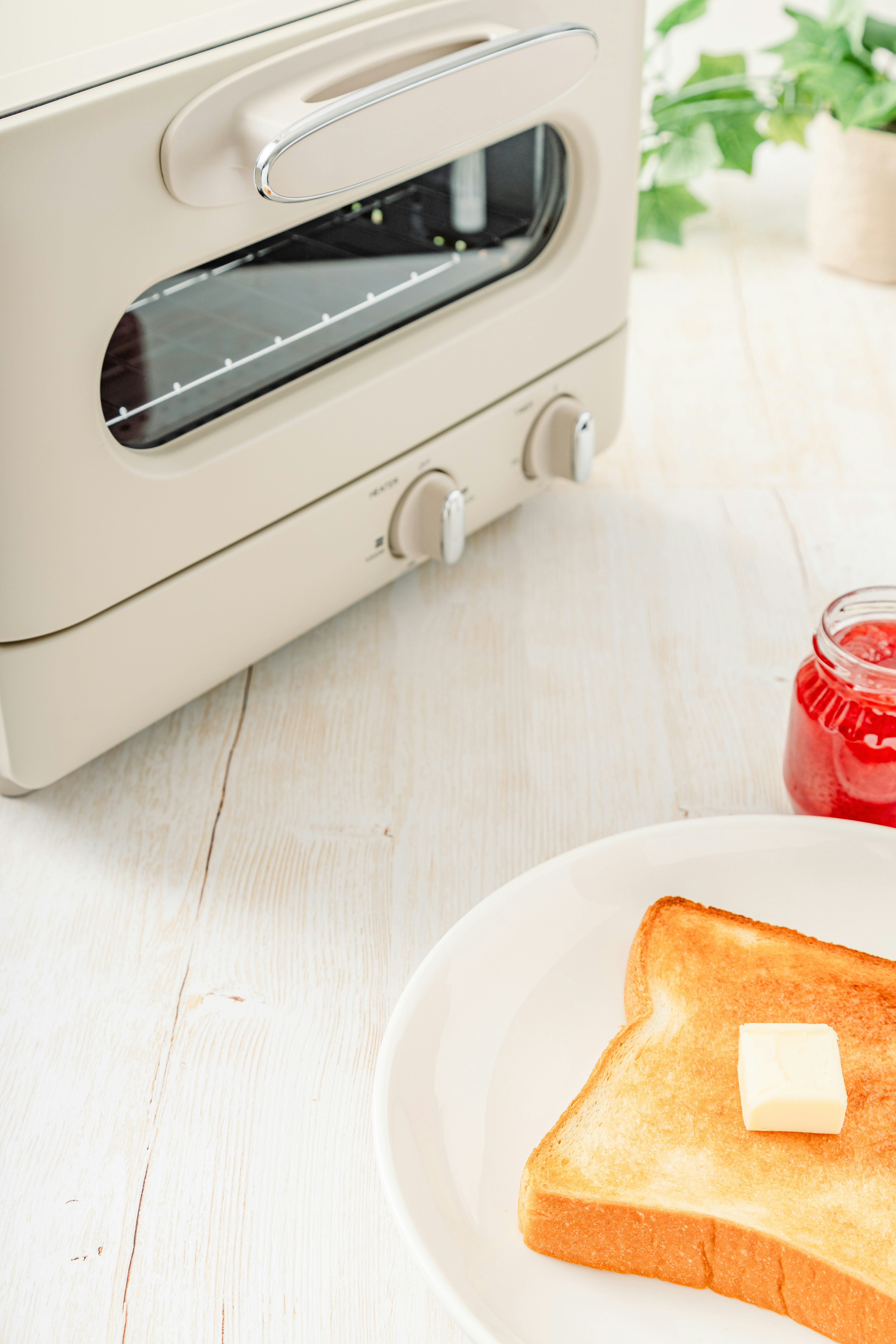 Une scène avec un grille-pain, une tranche de pain grillé avec du beurre et un pot de confiture