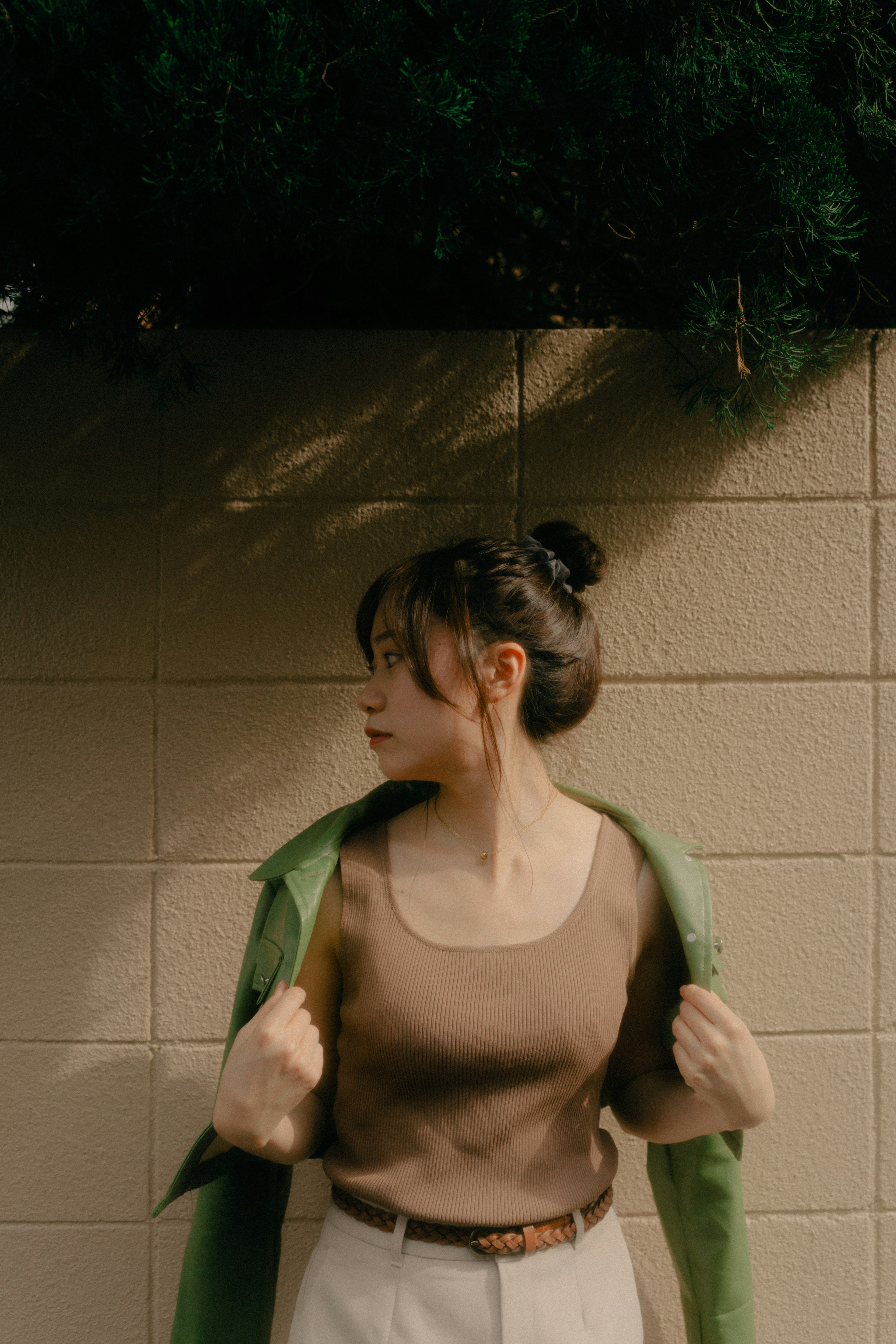 A woman holding a green jacket in front of a wall